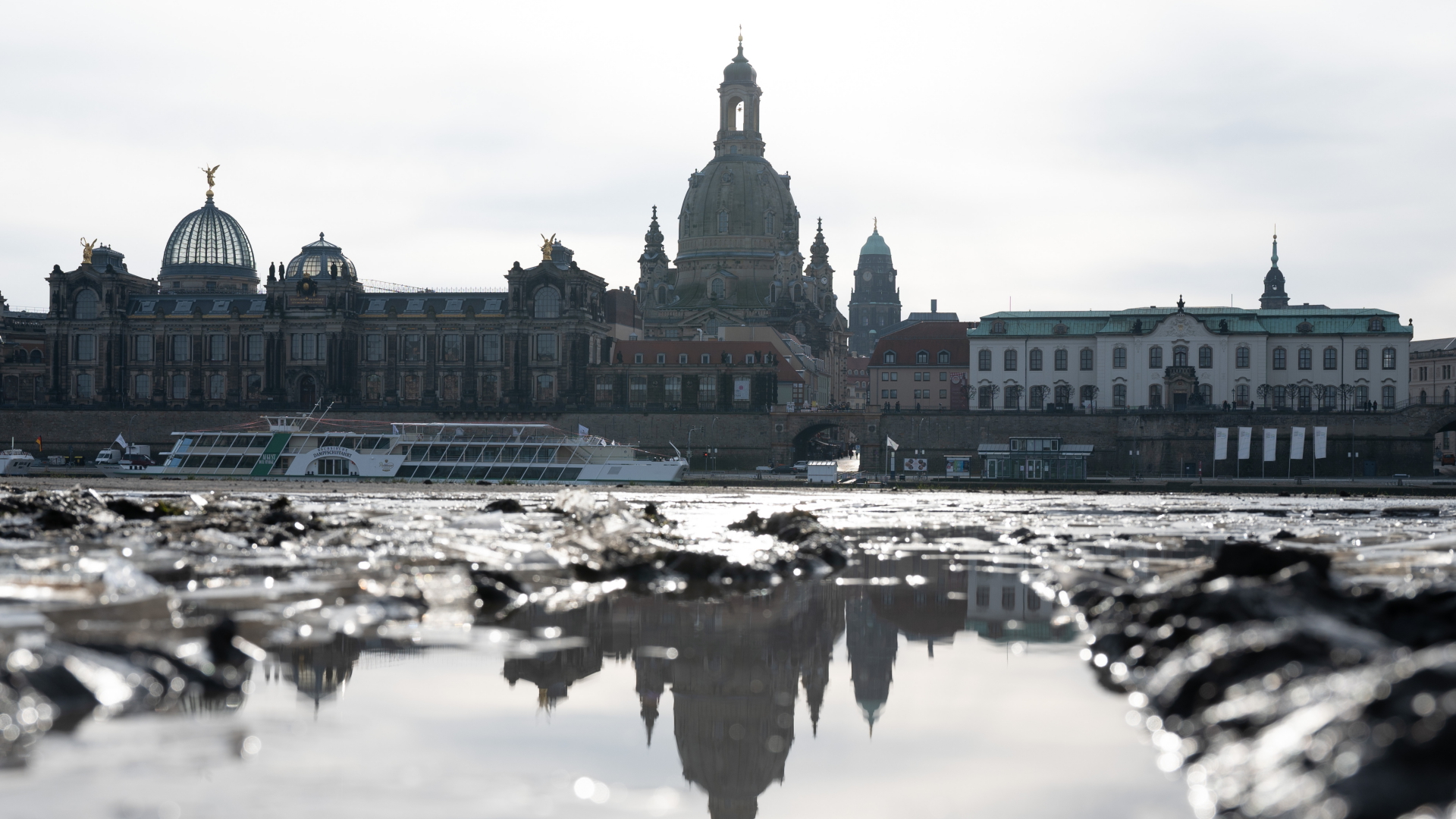 Die Frauenkirche spiegelt sich in Dresden am Ufer der Elbe in einer Pfütze. | dpa