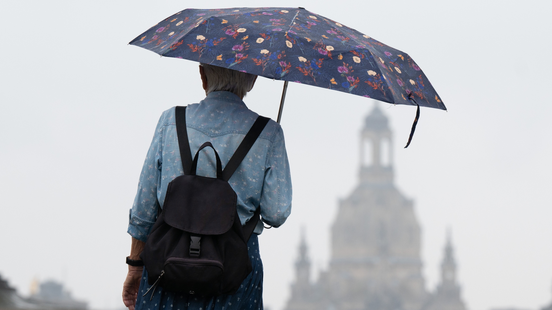 Eine Passantin mit Regenschirm an der Elbe in Dresden (Archivbild) | dpa