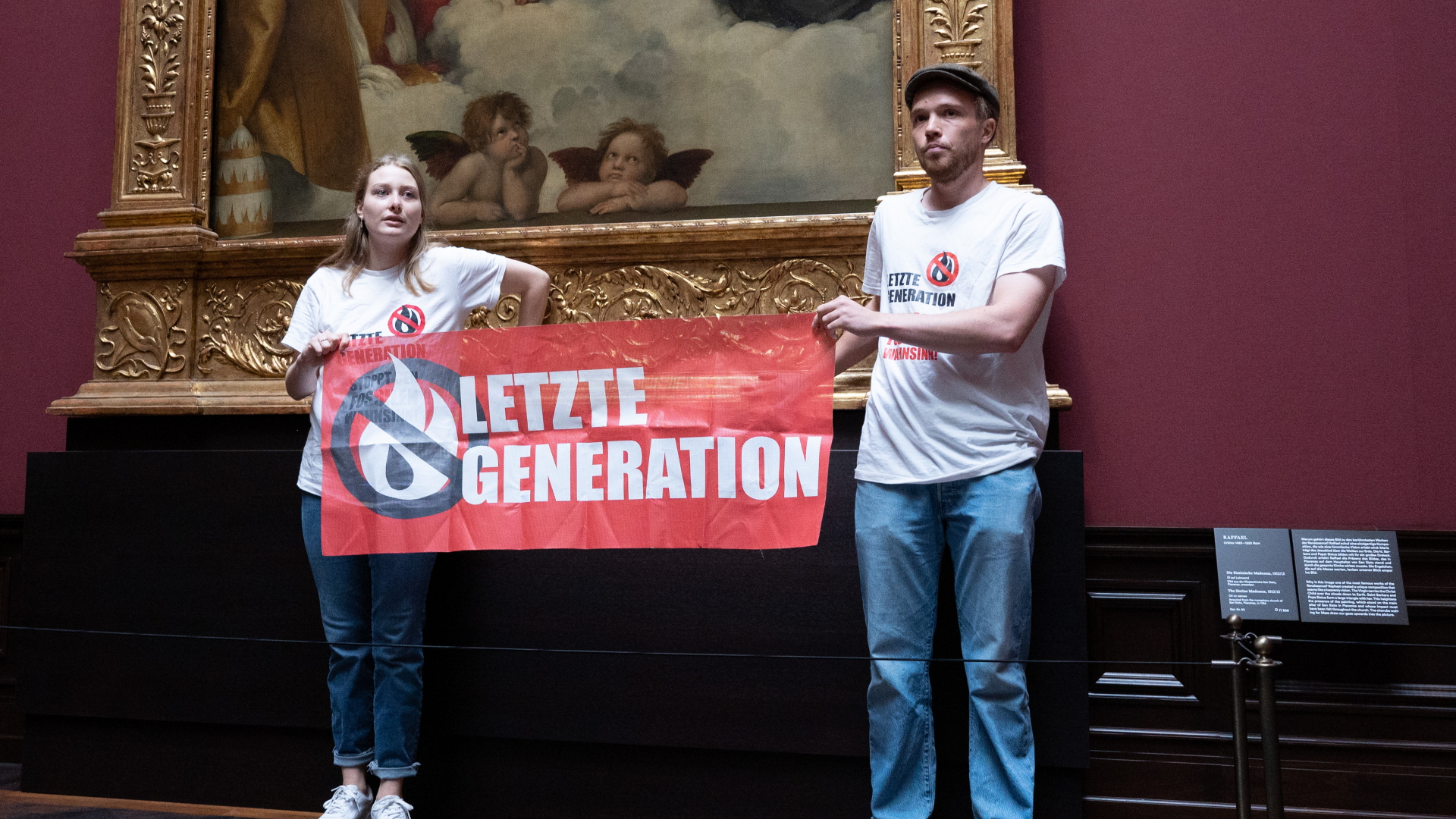 Zwei Umweltaktivisten der Gruppe "Letzte Generation" stehen mit einem Banner in der Gemäldegalerie Alte Meister an dem Gemälde ·Sixtinische Madonna· von Raffael. | dpa