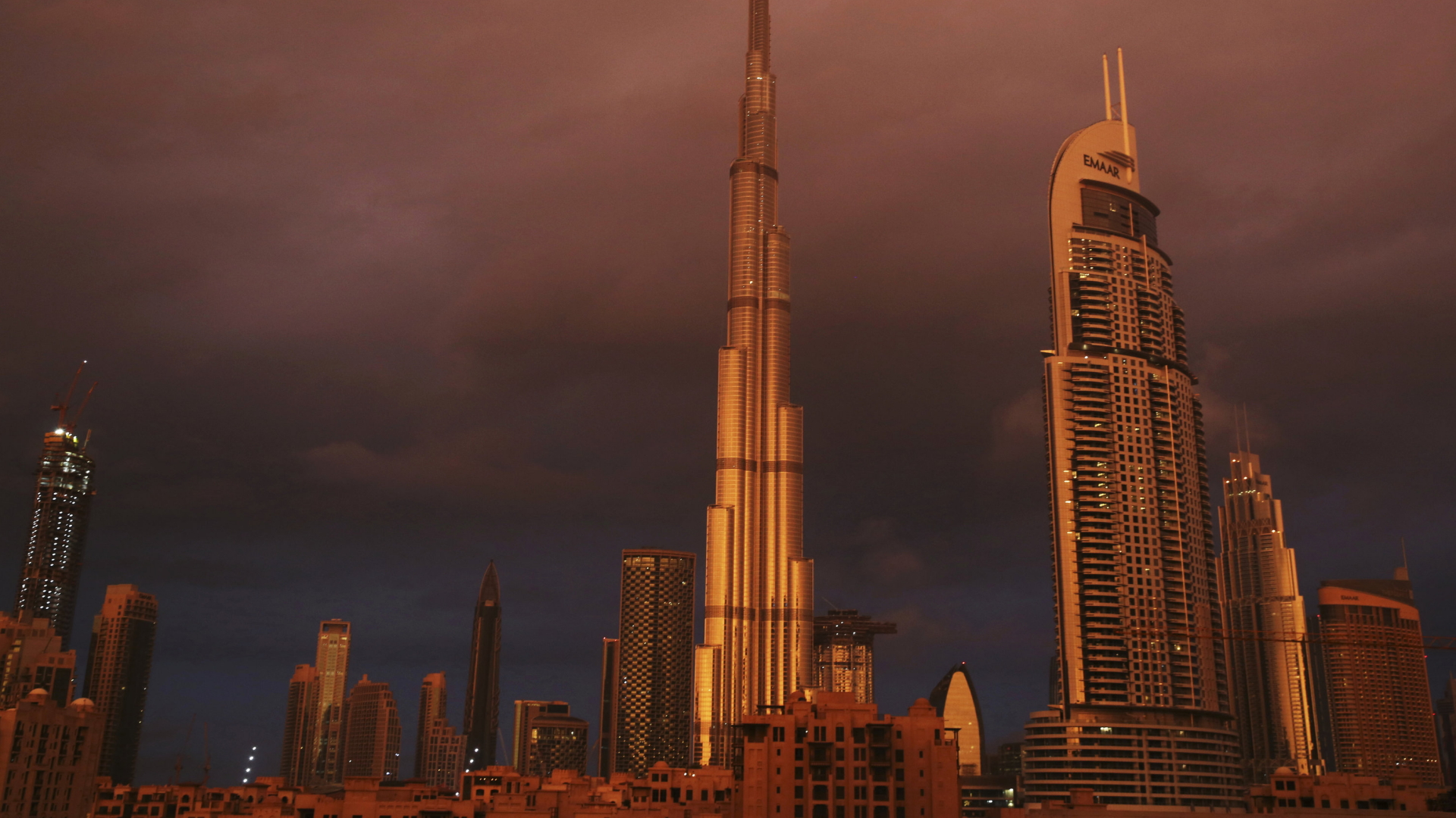 Der Burj Khalifa (links), das höchste Gebäude der Welt, wird während eines Regenschauers von der Sonne angestrahlt. | dpa