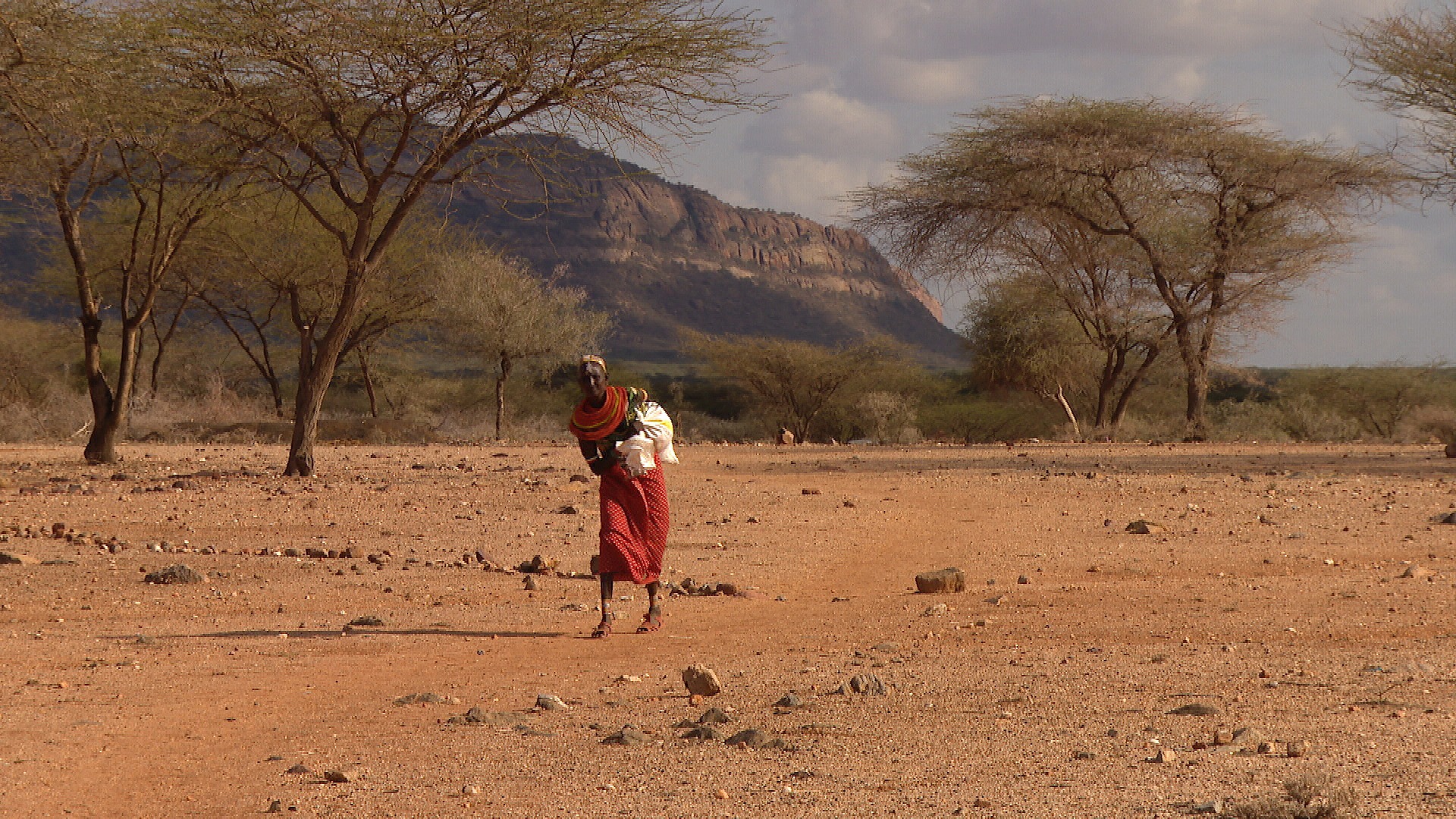 Die Kenianerin Ntereiyan Lenkegen trägt ihr Kleinkind auf dem Arm, während sie durch die Steppe läuft.