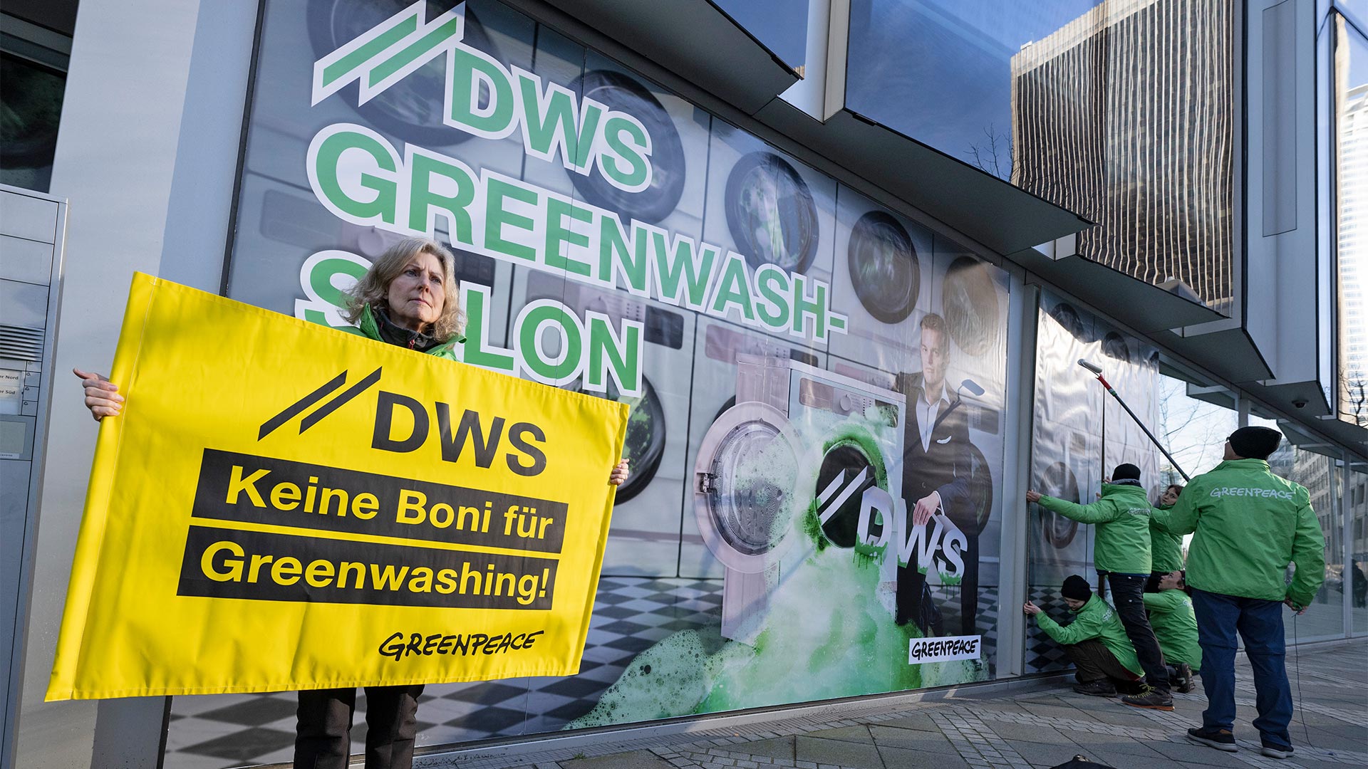Aktivistinnen von Greenpeace bekleben die Glasfassade der Deutsche-Bank-Tochter DWS in Frankfurt mit Bildern eines „Waschsalons“. Damit wollen die Aktivisten gegen die Nachhaltigkeitspolitik von DWS protestieren.