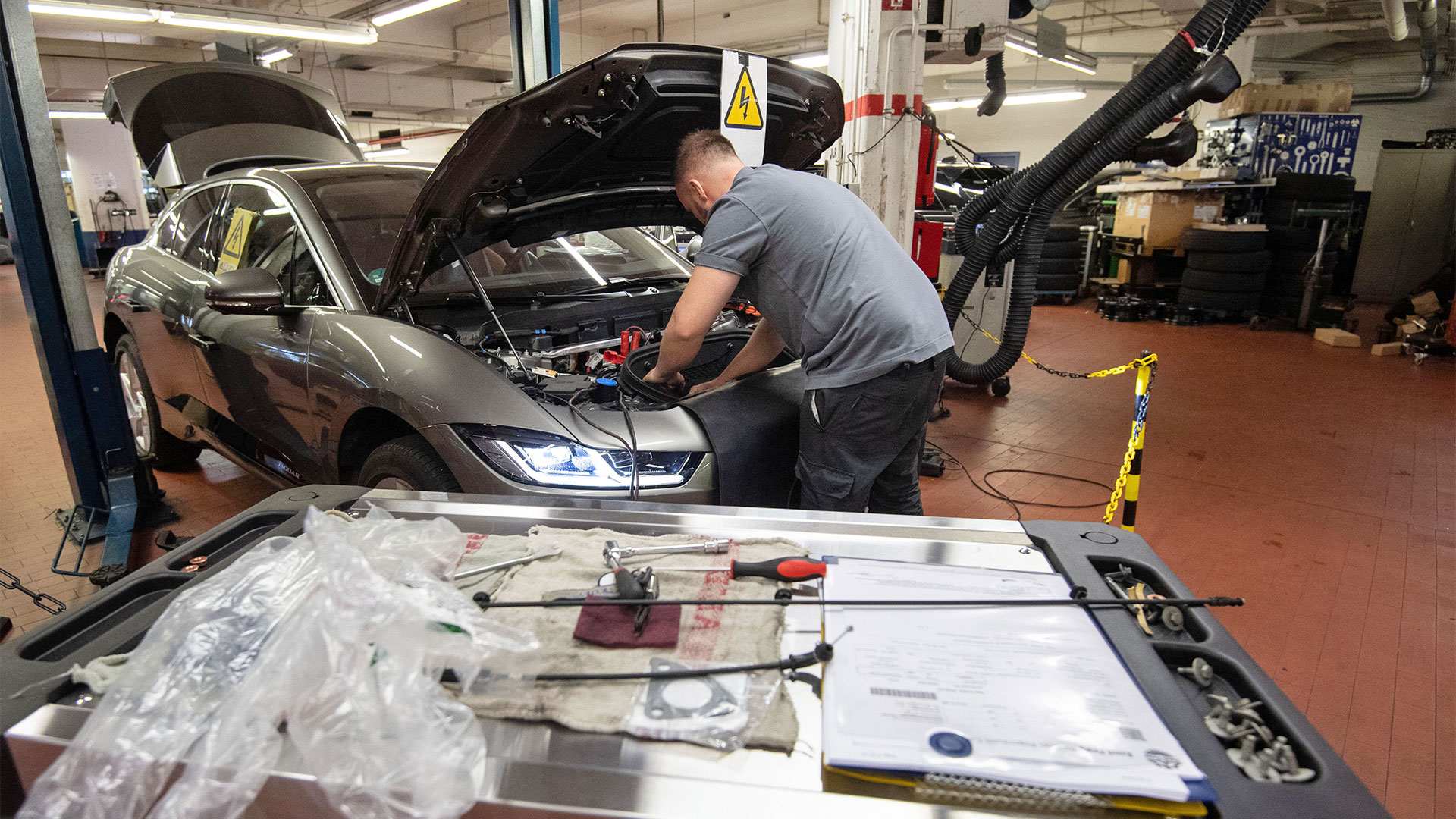 Ein KFZ-Mechaniker wartet in einer Werkstatt einen elektrisch angetriebenen Jaguar I-Pace. | picture alliance/dpa