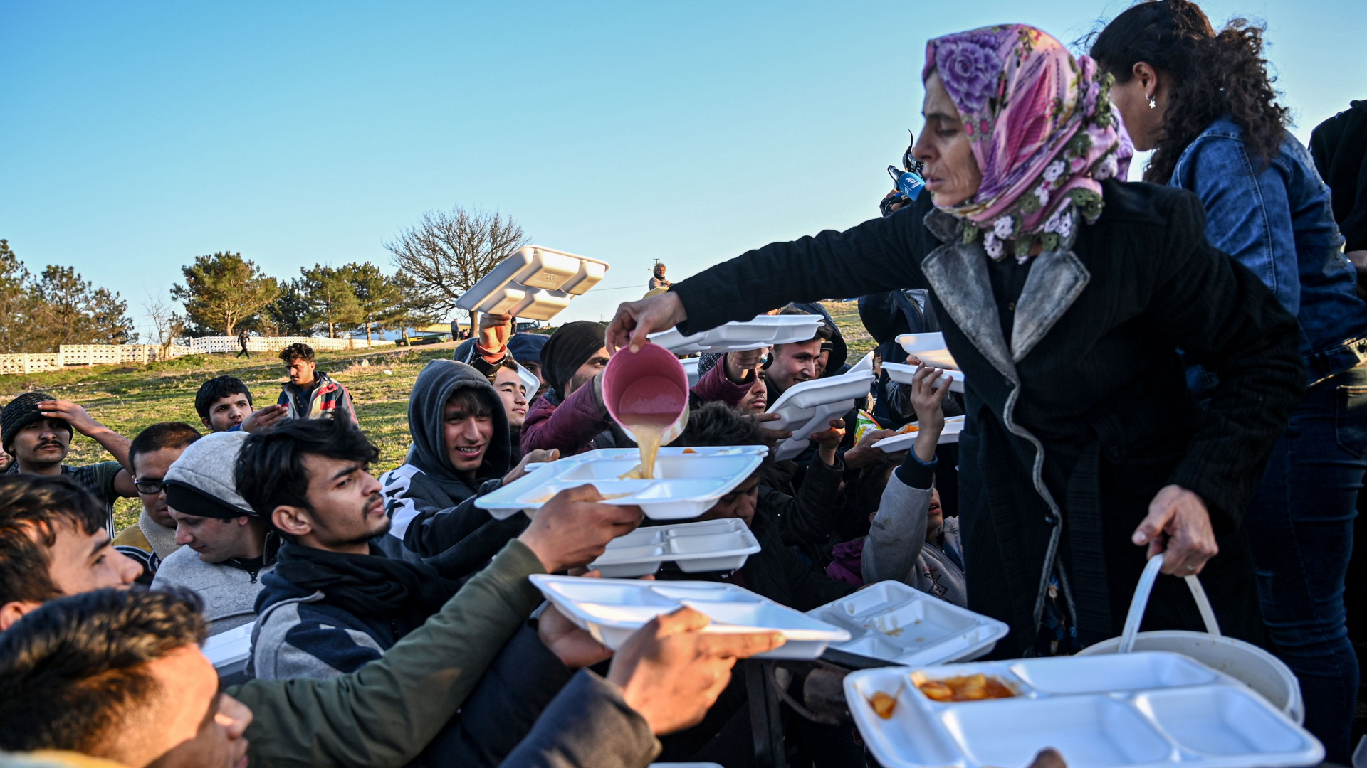 Helferinnen verteilen Essen an Geflüchtete an der griechisch-türkischen Grenze bei Edirne. | AFP