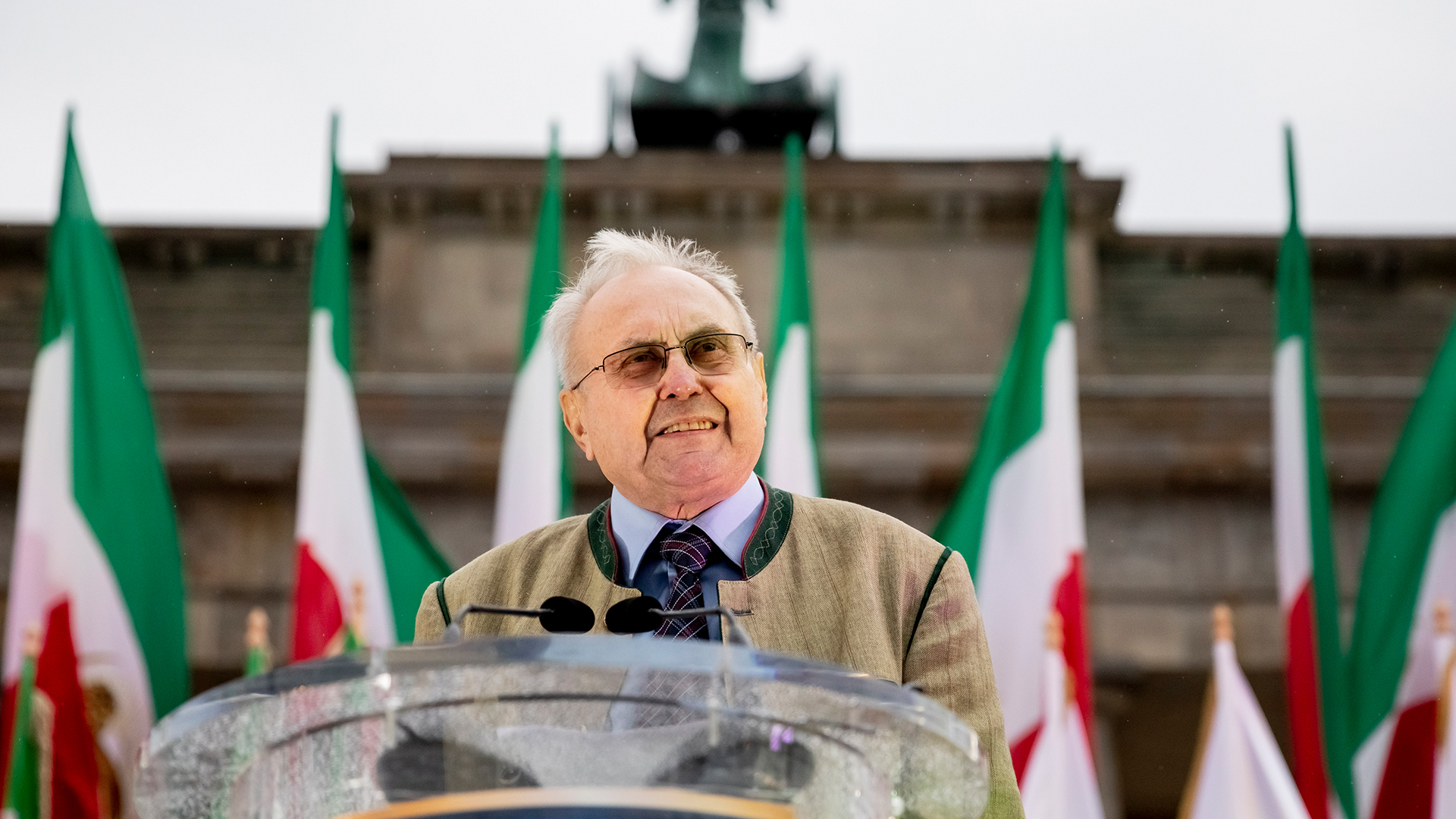 Eduard Lintner spricht vor dem Brandenburger Tor - davor iranische Flaggen | picture alliance/dpa