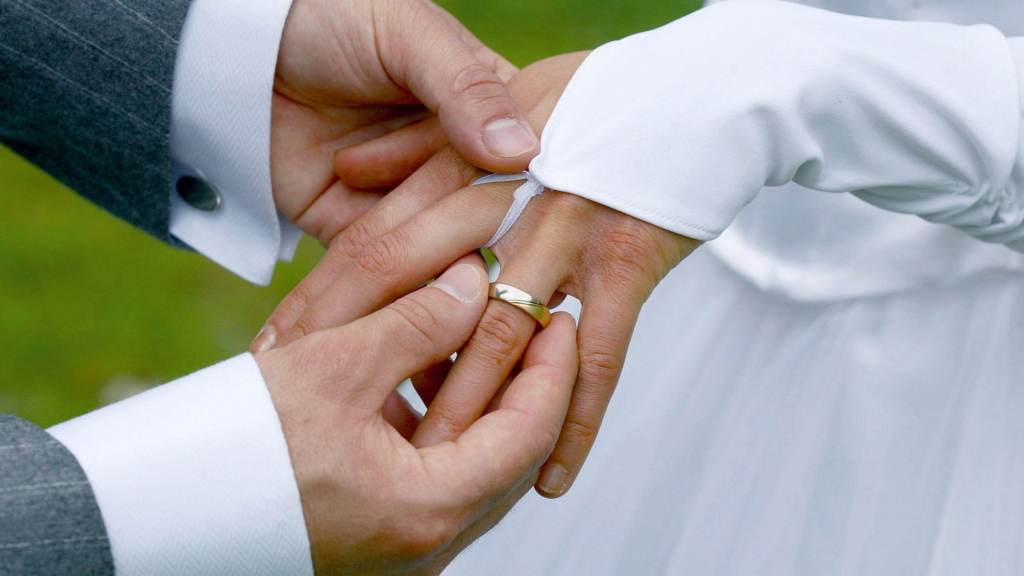 Ein Bräutigam streift bei der Trauung seiner Braut den Ehering über den Finger. | dpa