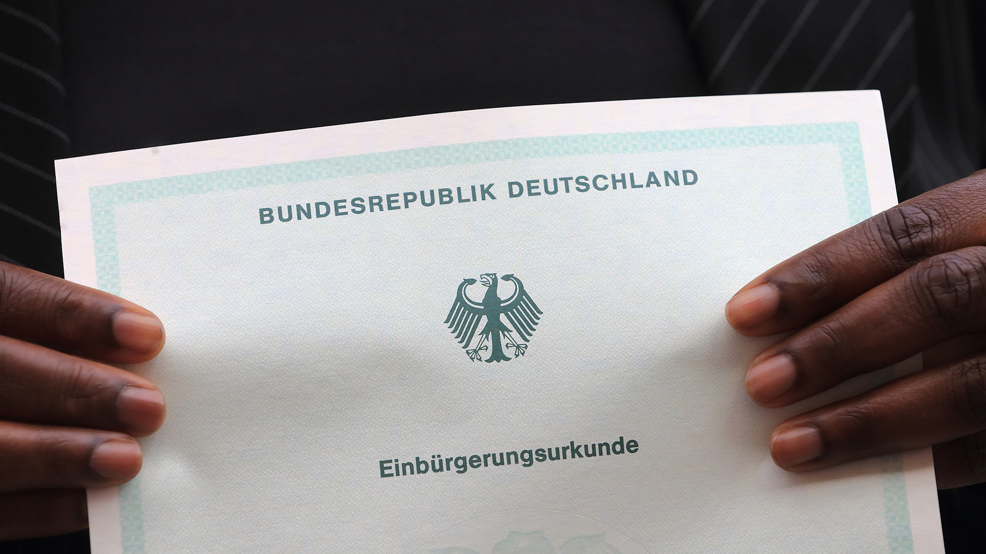 Eine in Afrika geborene Frau hält ihre Einbürgerungsurkunde der Bundesrepublik Deutschland in ihren Händen. (Archivbild)