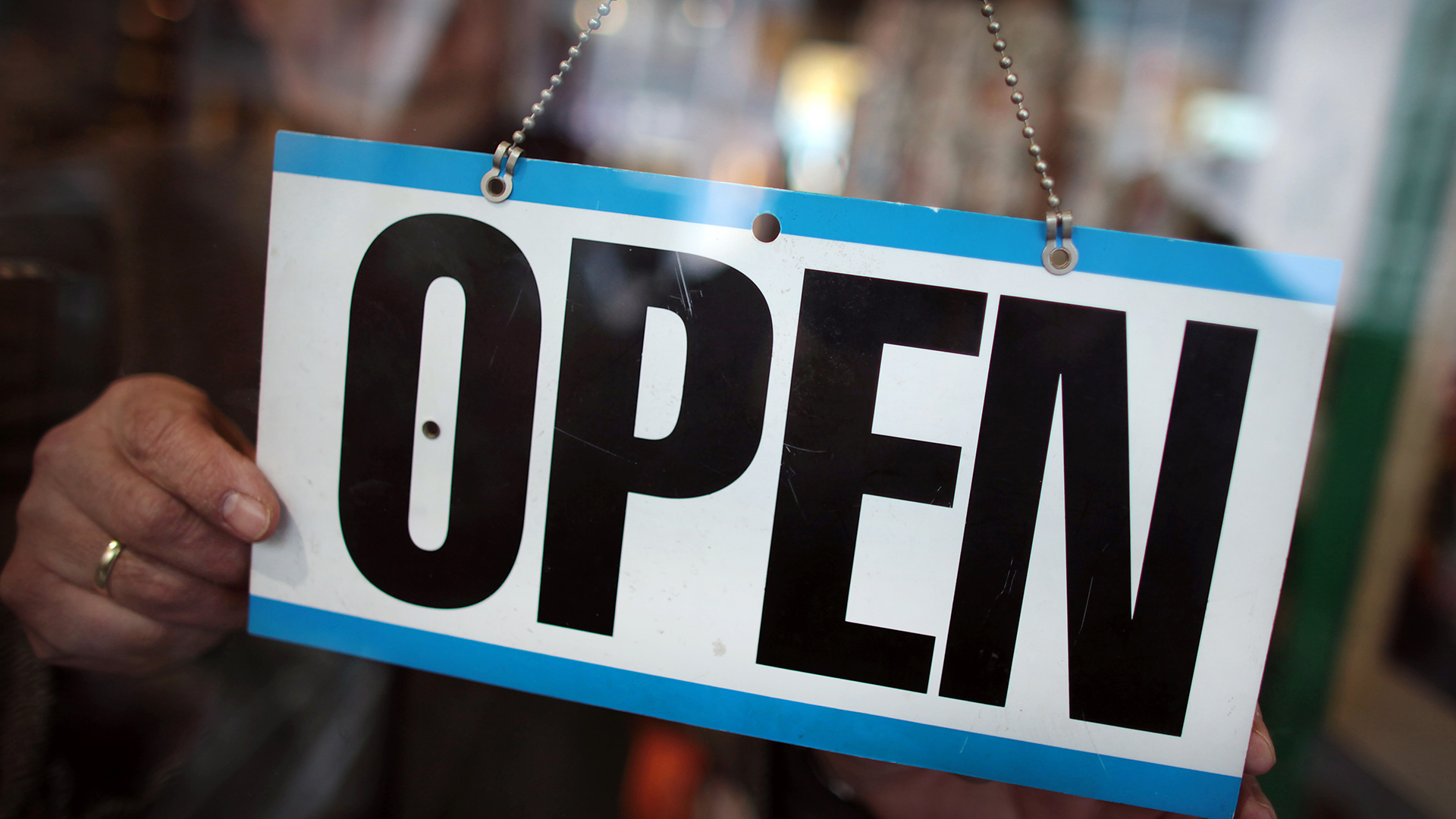  Ein Ladeninhaber dreht an seinem Geschäft das Schild auf "open". | picture alliance/dpa