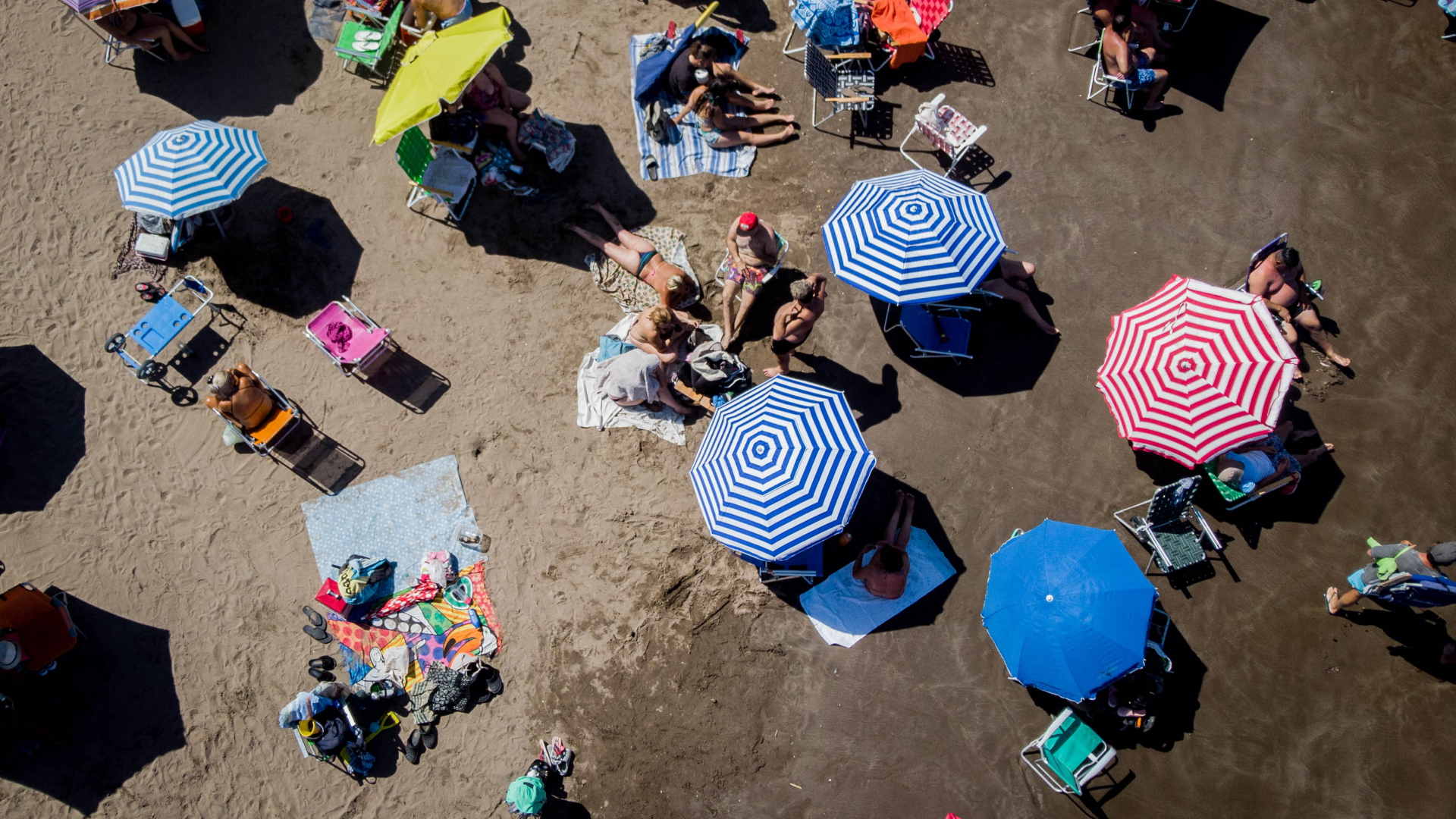 Menschen liegen unter Sonnenschirmen am Strand in Mar Del Plata, Argentinien