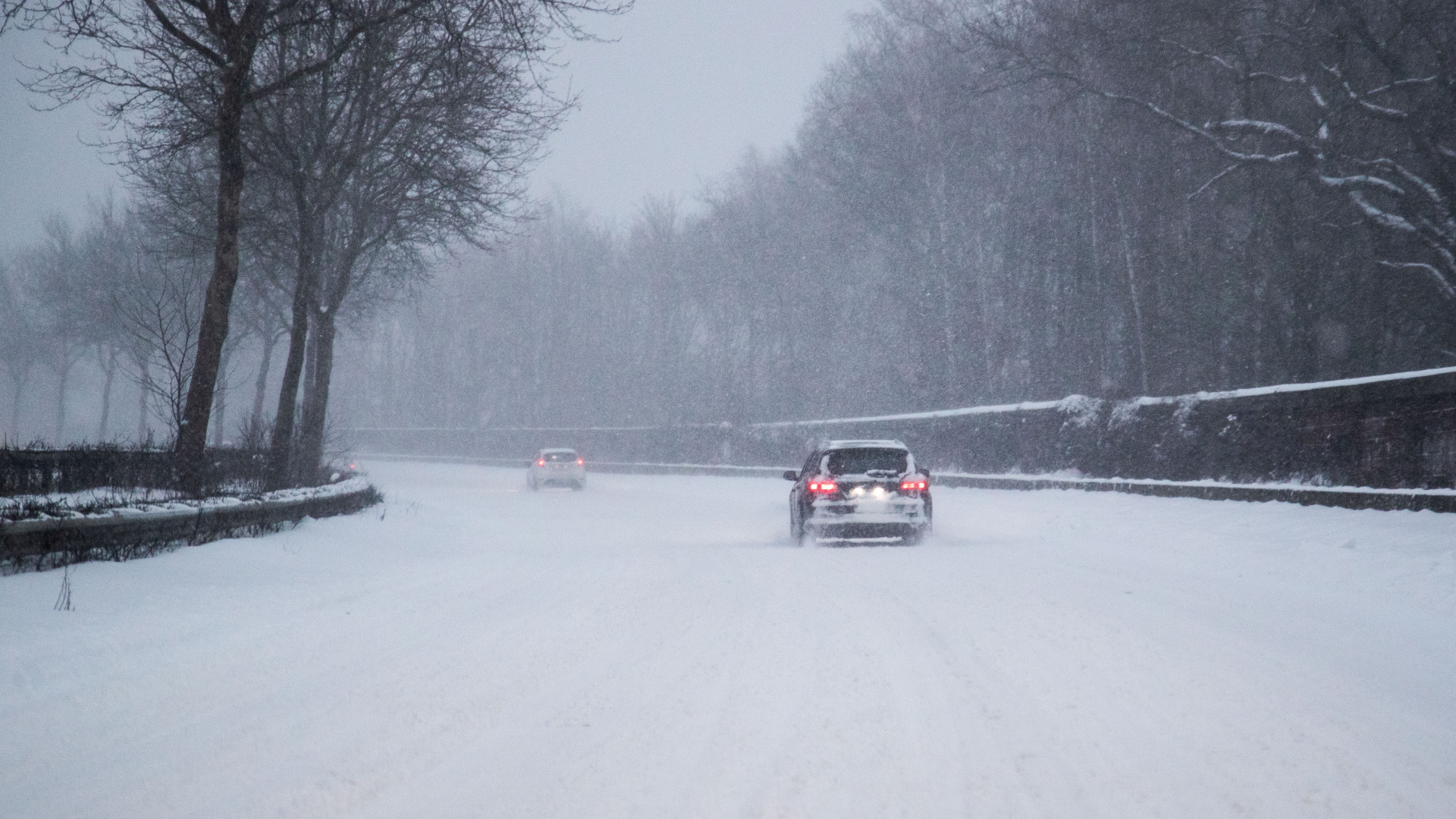 Nordrhein-Westfalen, Bielefeld: Nur vereinzelt fahren Autos auf einer zugeschneiten Straße.