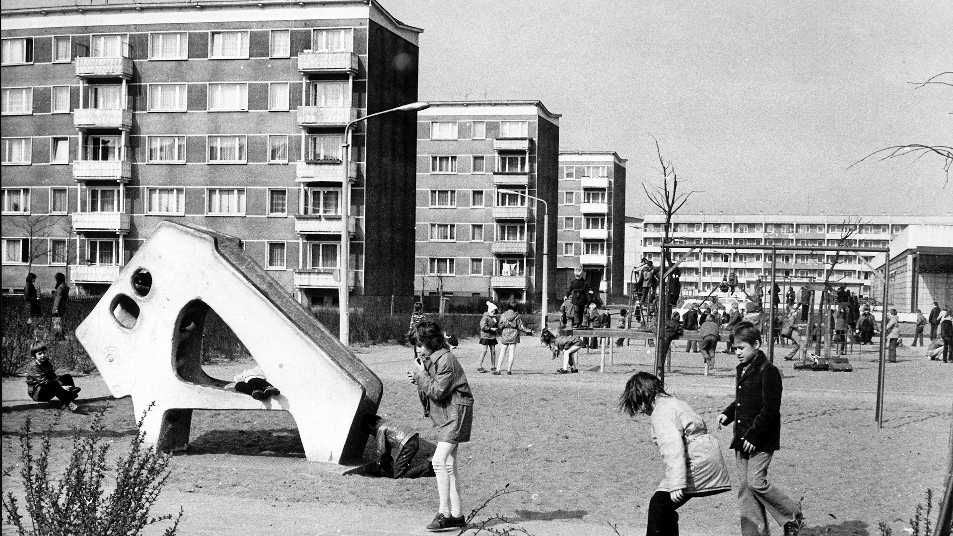 Kinder spielen auf einem Kinderspielplatz vor Plattenbauten in einem Neubauviertel (Archivbild von 1974) | picture alliance/dpa
