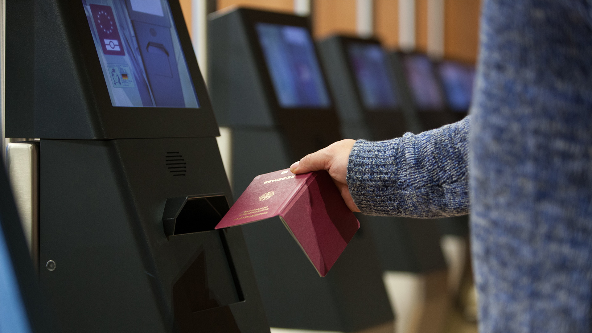 Ein Mann steht am Flughafen vor einem eGate und lässt seinen Reisepass scannen