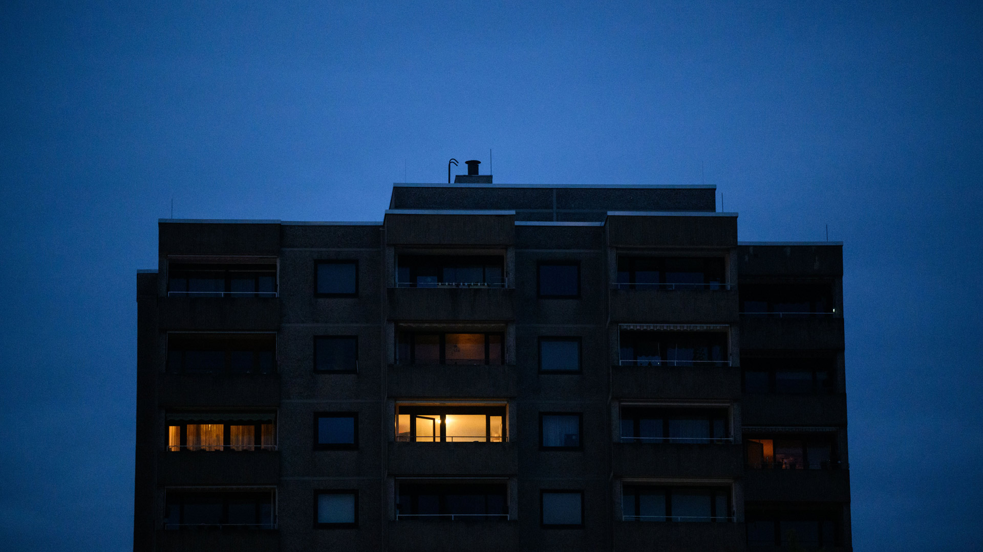 Nur in einzelnen Wohnungen eines Mehrfamilienhauses brennt am frühen Morgen Licht. | picture alliance/dpa