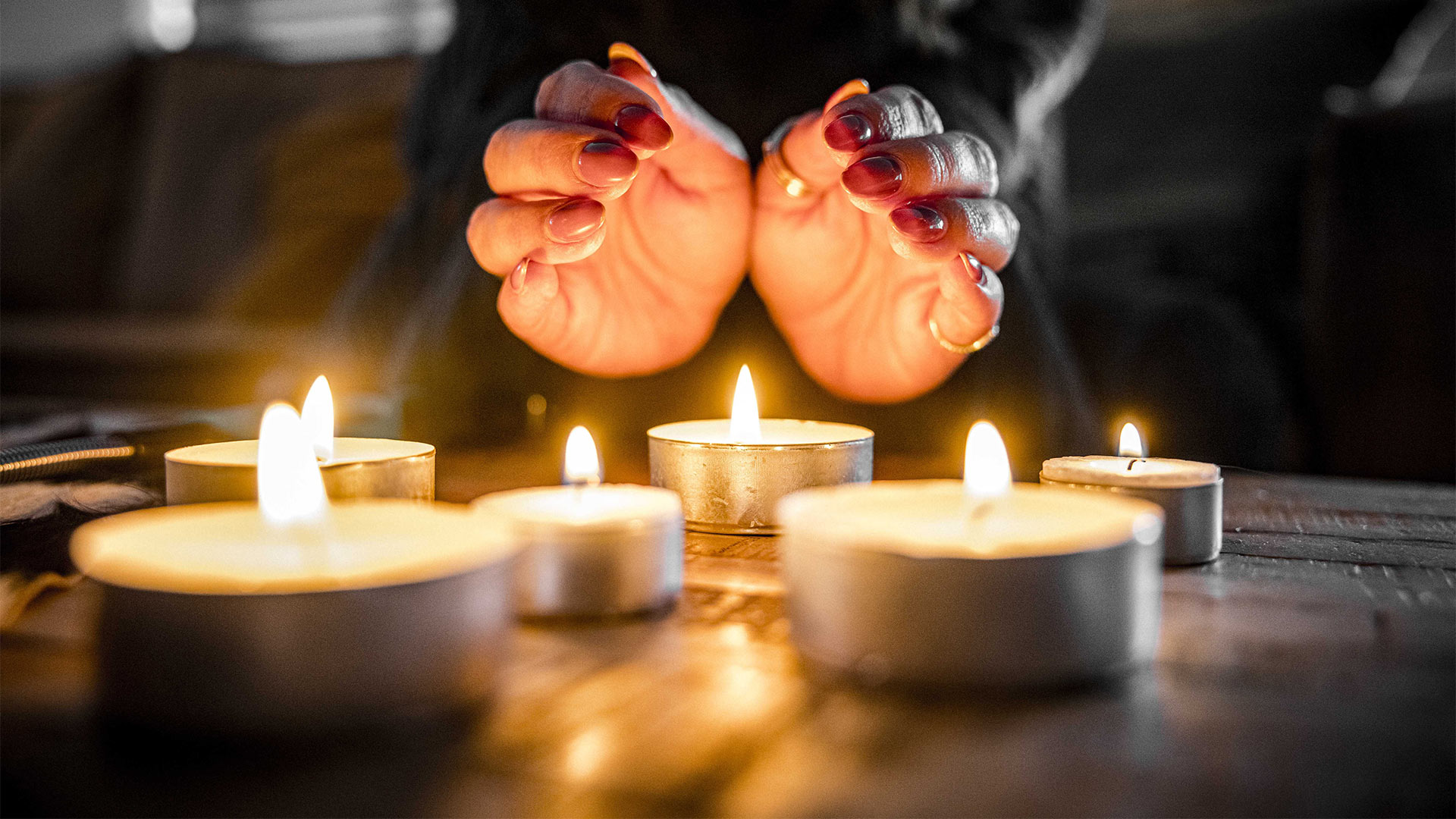 Eine Frau wärmt sich mit Kerzen, um Energie zu sparen.