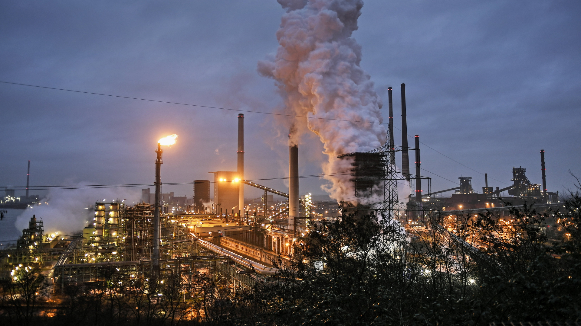 Rauchende Schlote vor dunklem Himmel  einer Kokerei von ThyssenKrupp in Duisburg (Archivbild: Januar 2020). | AP