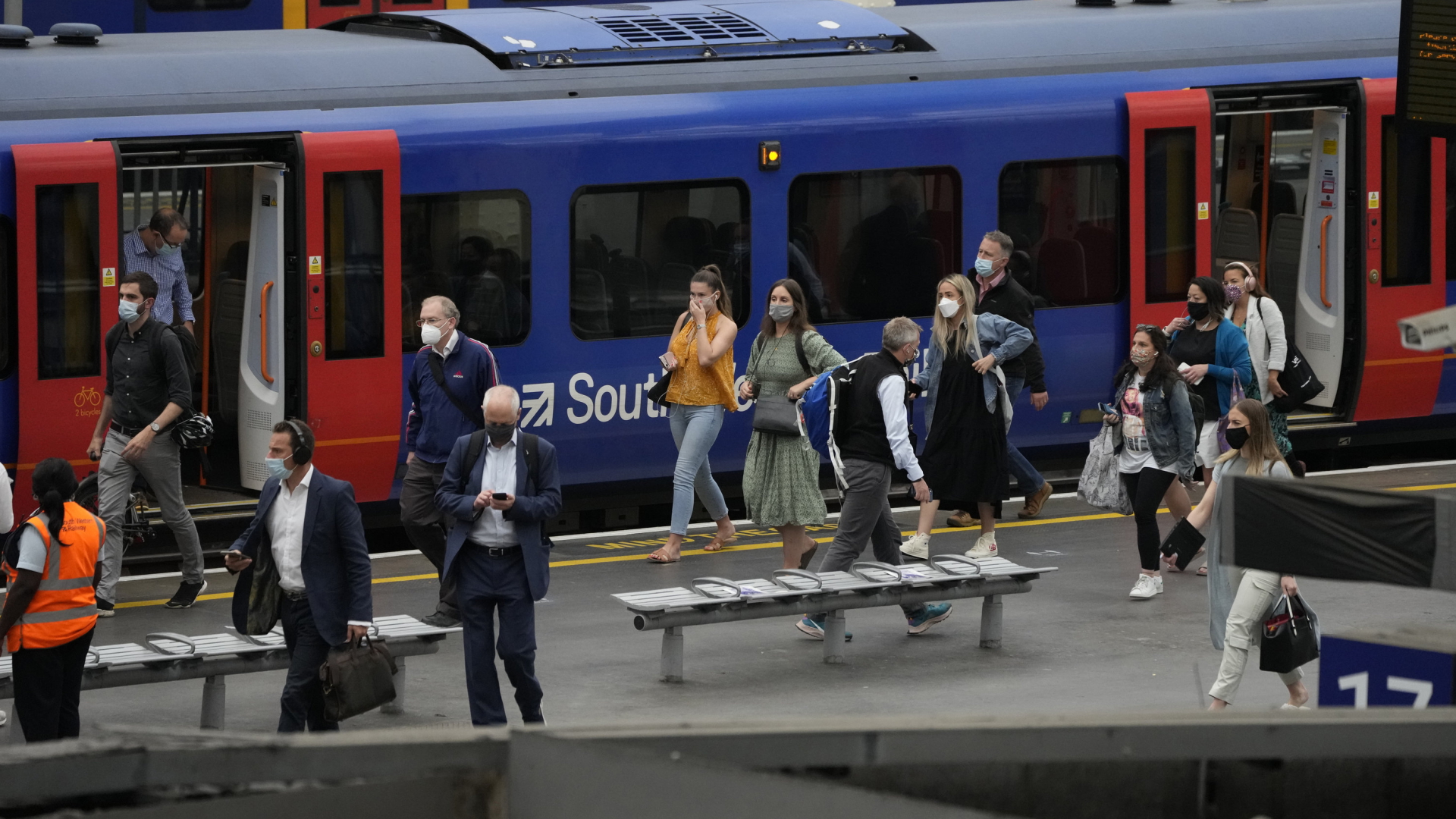 Menschen mit Schutzmasken verlassen einen Zug am Bahnhof Waterloo in London. | AP