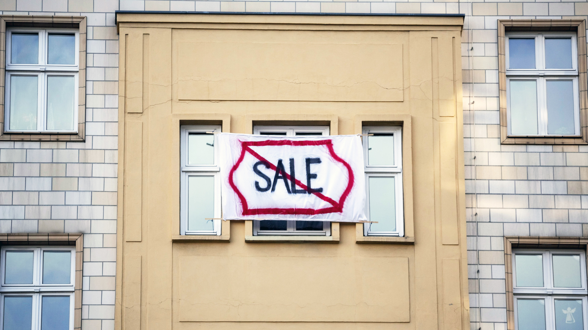 Ein Plakat gegen den Verkauf von Mietwohnungen an die Deutsche Wohnen mit dem durchgestrichenen Wort "Sale" hängt an einer Gebäudefassade.