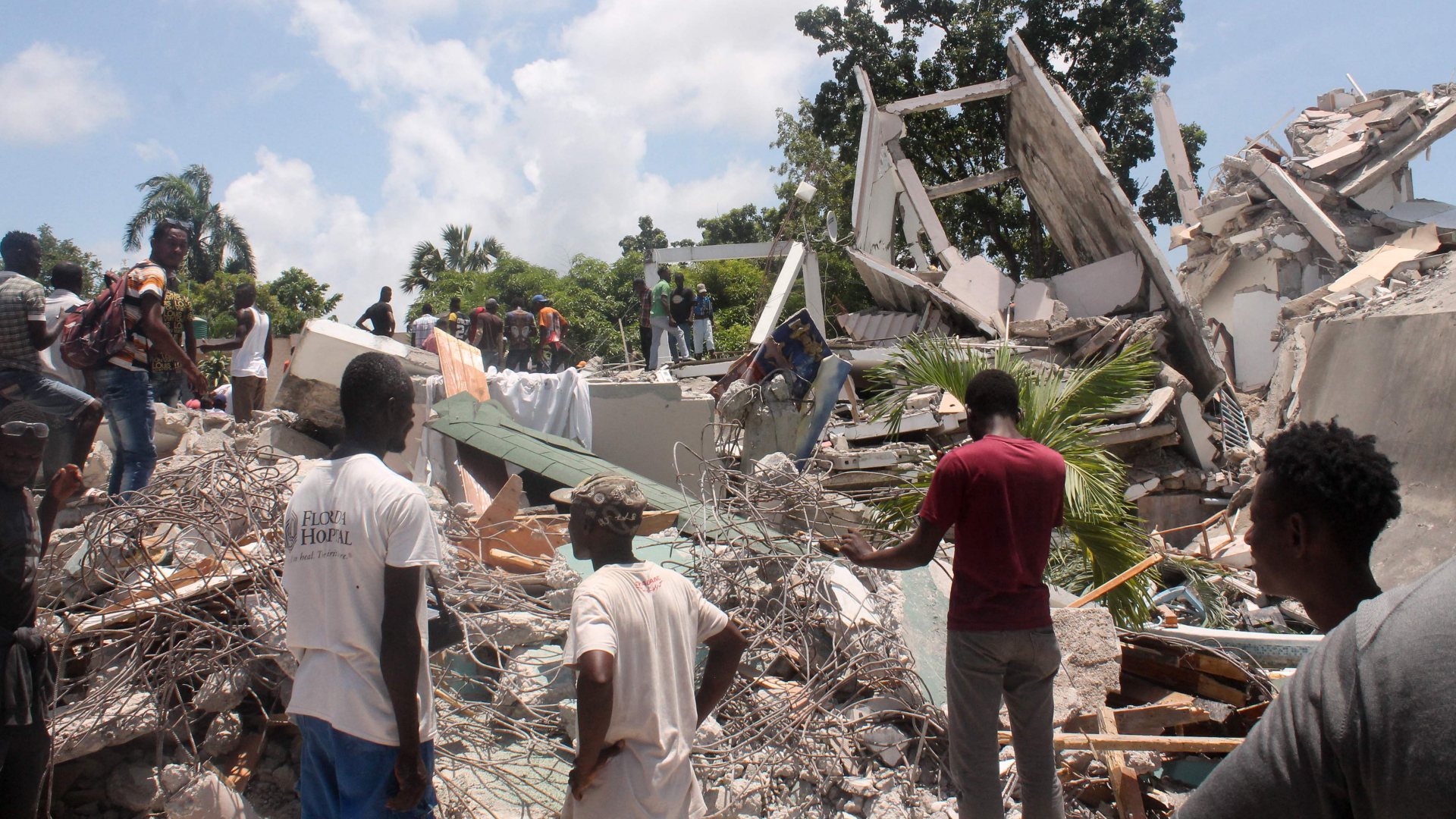 Menschen stehen nach dem Erdbeben vor einem ehemaligen Hotel in Les Cayes, Haiti. | AFP