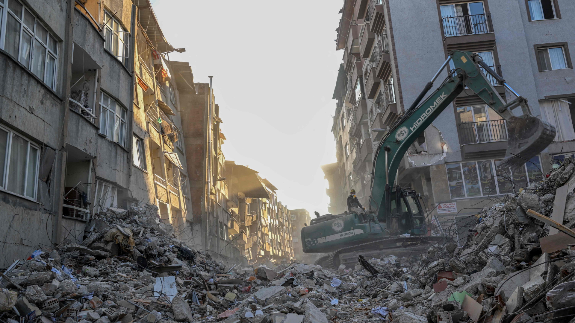 Ein Bagger beseitigt Trümmer inmitten eingestürzter Gebäude in Hatay | AFP