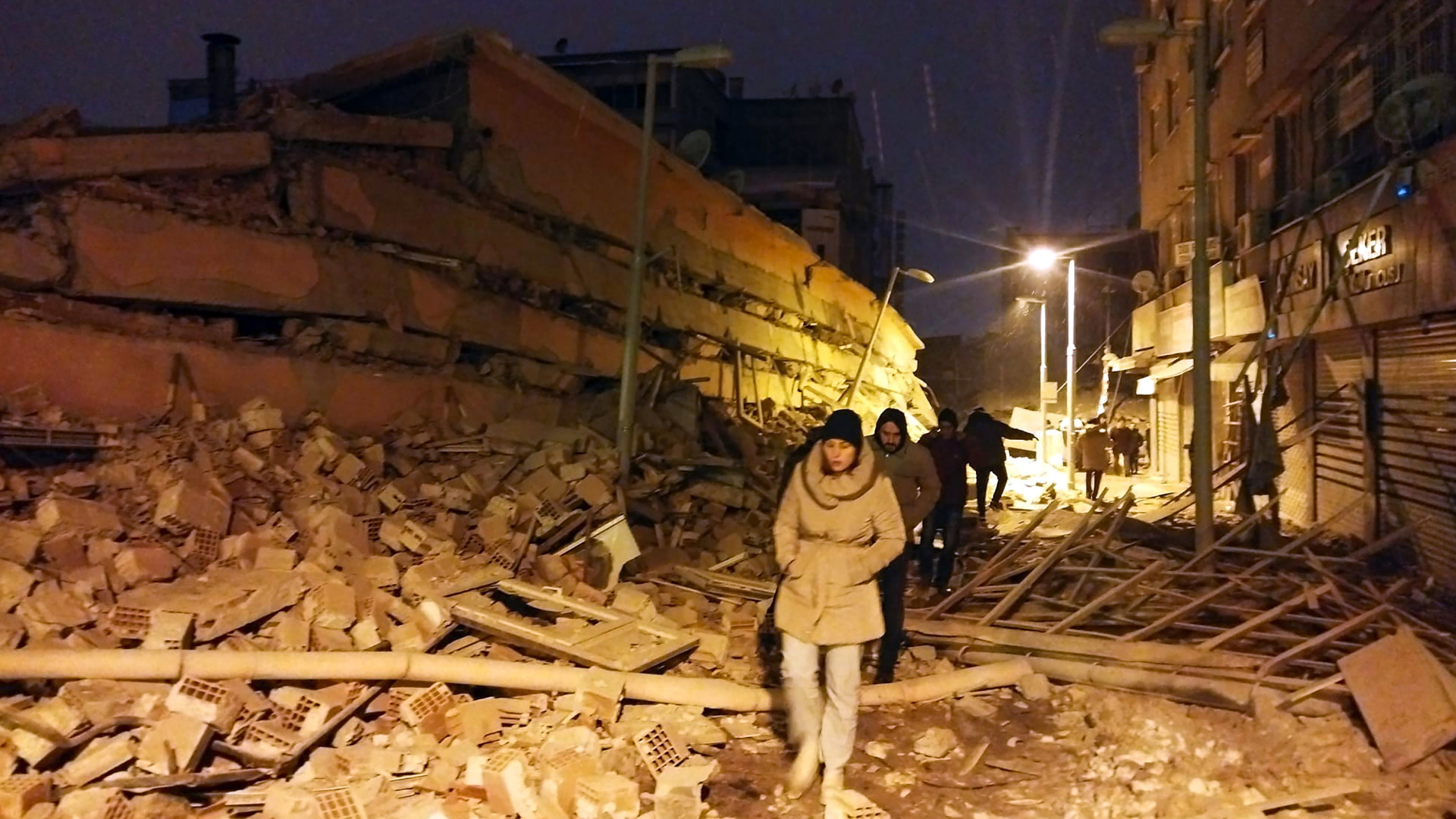 Menschen laufen in der Stadt Malatya in der Türkei nach schweren Erdbeben über Trümmer von zerstörten Gebäuden. | AP