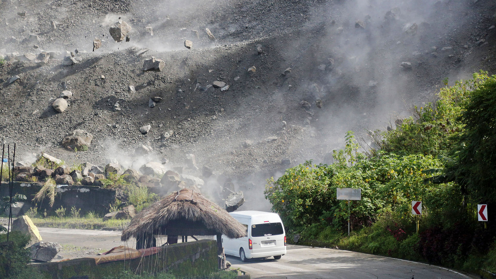 Felsbrocken stürzen herab, als ein Fahrzeug während eines Erdbebens im philippinischen Bauko eine Straße befährt. | AP