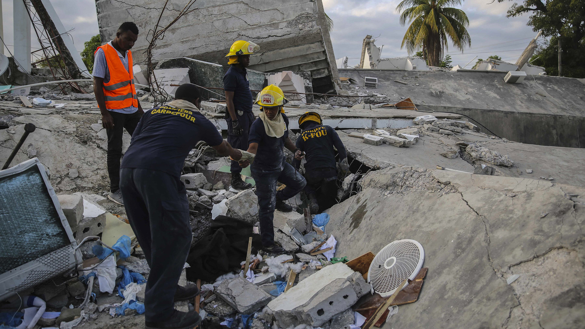 Helfer suchen in den Trümmern eines Hauses nach Überlebenden. | AP