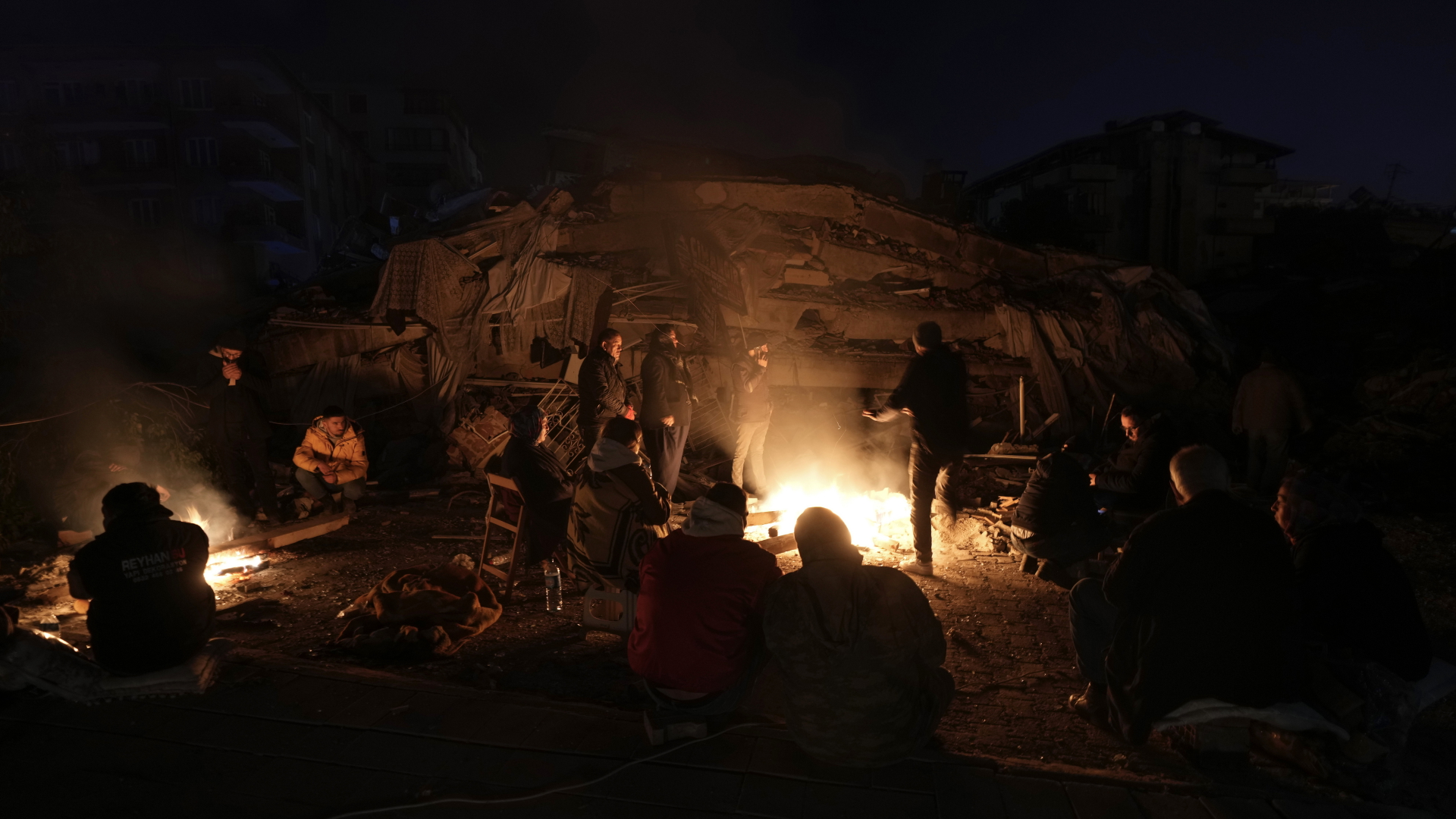 Überlebende kampieren vor Trümmern im türkischen Erdbebebgebiet.
