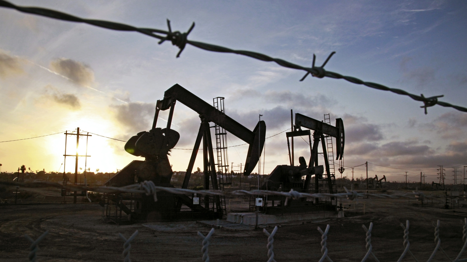Die Sonne geht jenseits der auf den Ölfeldern von Inglewood bei Los Angeles arbeitenden Öl-Tiefpumpen unter.