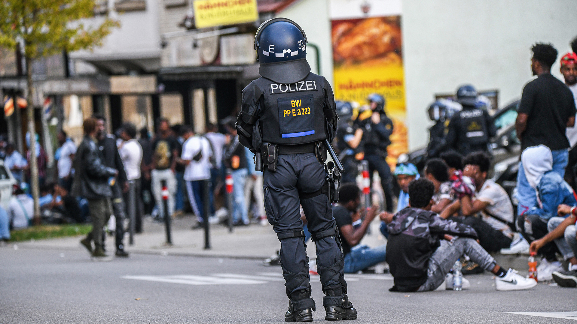 Polizisten stehen zwischen Gruppen von Menschen auf der Straße.