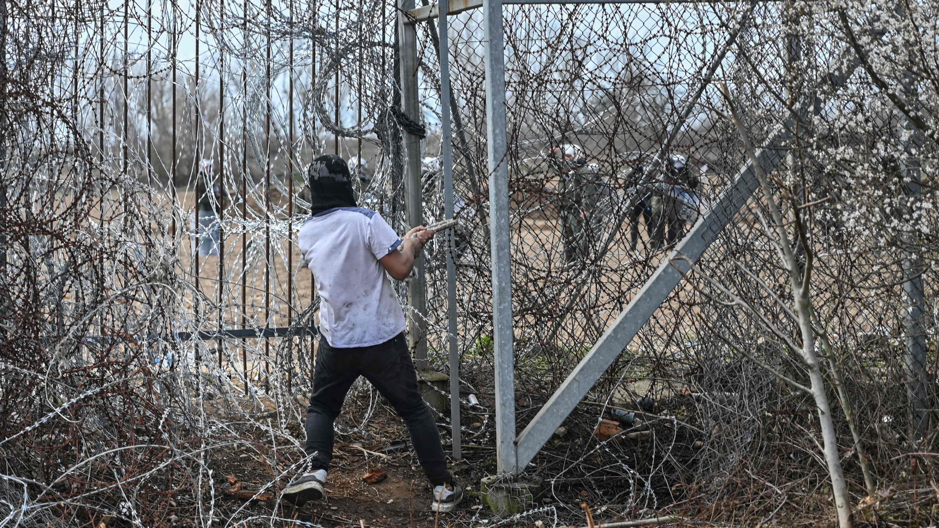Ein Mann versucht durch den Zaun an der EU-Außengrenze beim türkischen Edirne zu dringen (Archivbild März 2020). | AFP