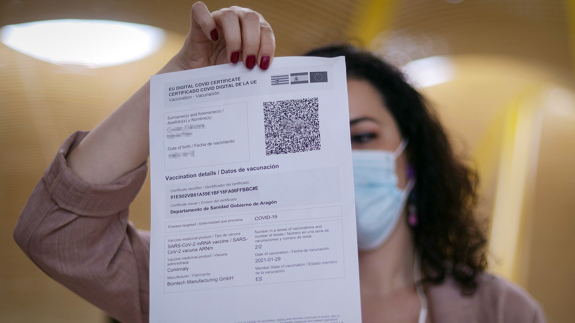 Eine Frau hält ein ausgedrucktes EU-Covid-Zertifikat hoch | dpa