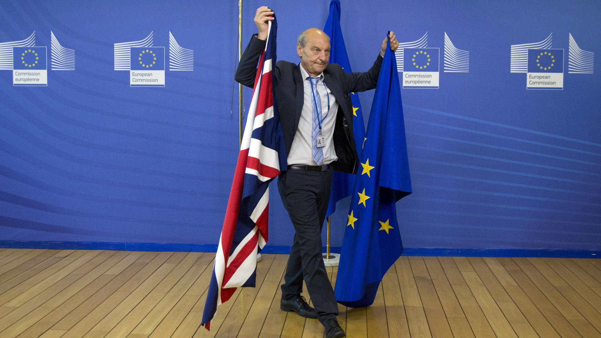 Ein Kommissionsmitarbeiter stellt die britische und die EU-Flagge um (Archivbild) | AP