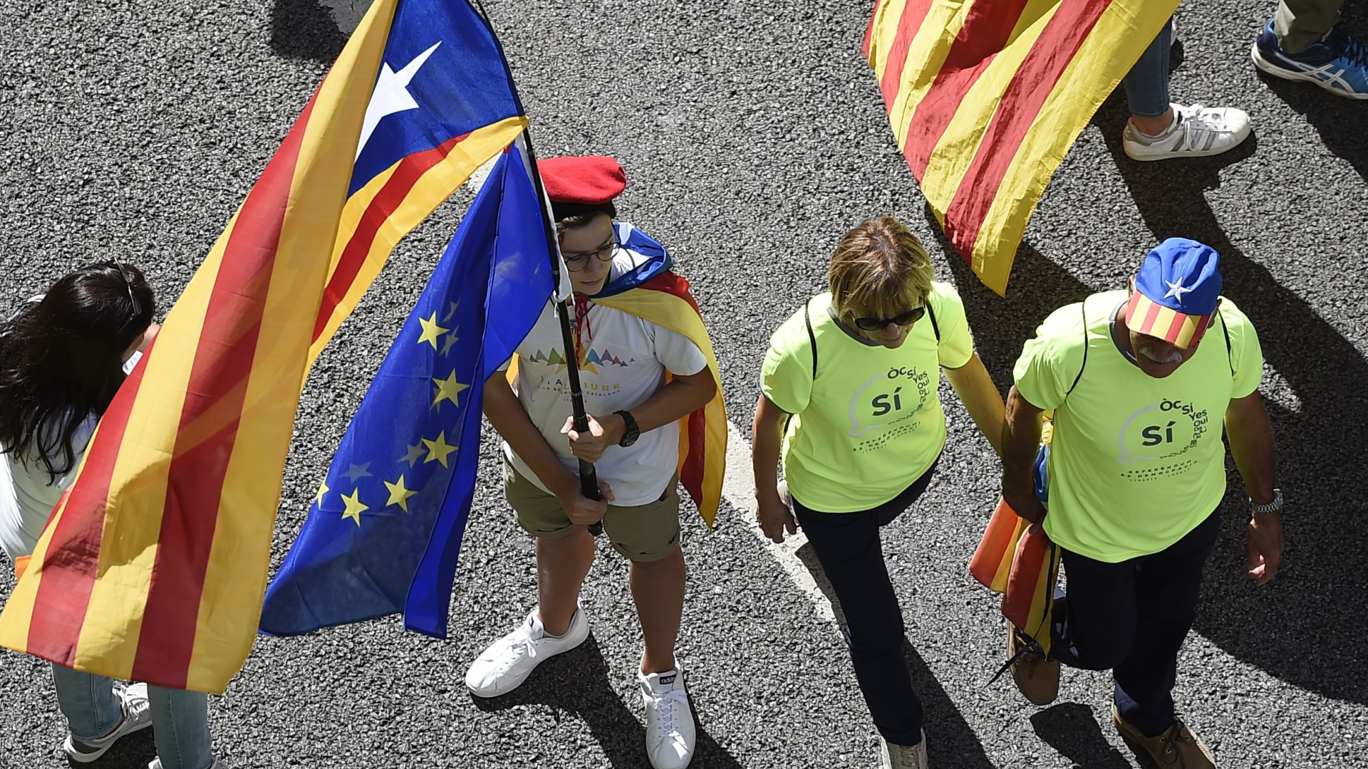 Ein Mann hält eine katalonische Unabhängigkeitsfahne sowie eine Fahne der EU