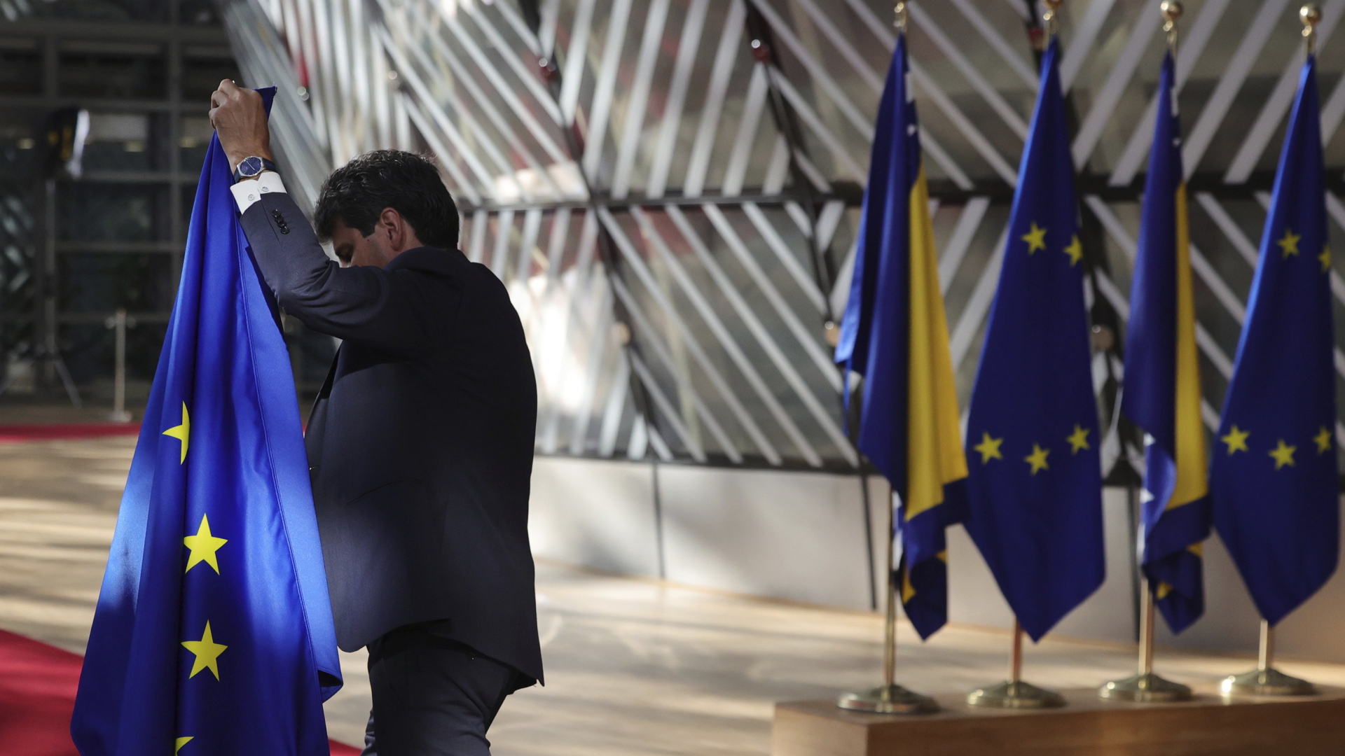 Ein Mann stellt vor dem EU-Westbalkan-Gipfel die EU-Flagge in Brüssel auf | AP