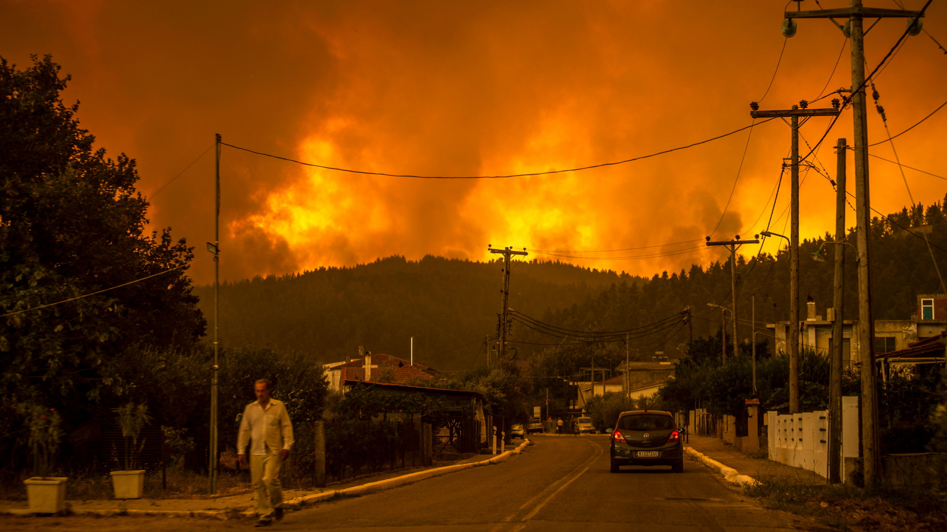 Ein Anwohner geht eine Straße auf der Insel Euböa entlang, während auf der zweitgrößten griechischen Insel des Landes ein Waldbrand tobt. | AFP