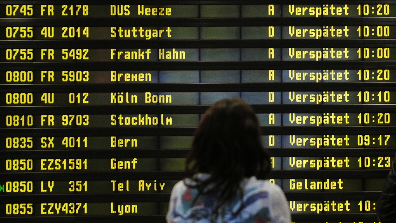 Eine Frau steht auf dem Flughafen Berlin-Schönefeld vor einer Anzeigetafel, auf der verspätete Flüge aufgelistet werden (Archivbild vom 10.12.2010). | dpa