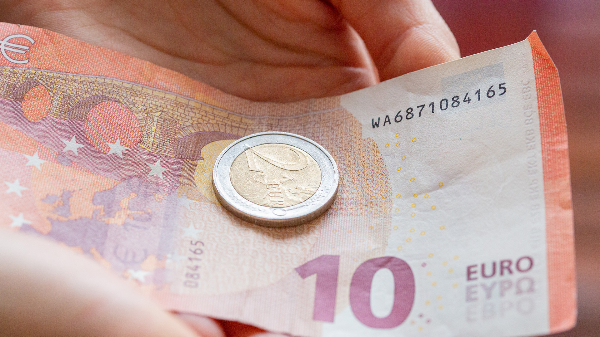 Eine Person hält 12 Euro in der Hand. | dpa