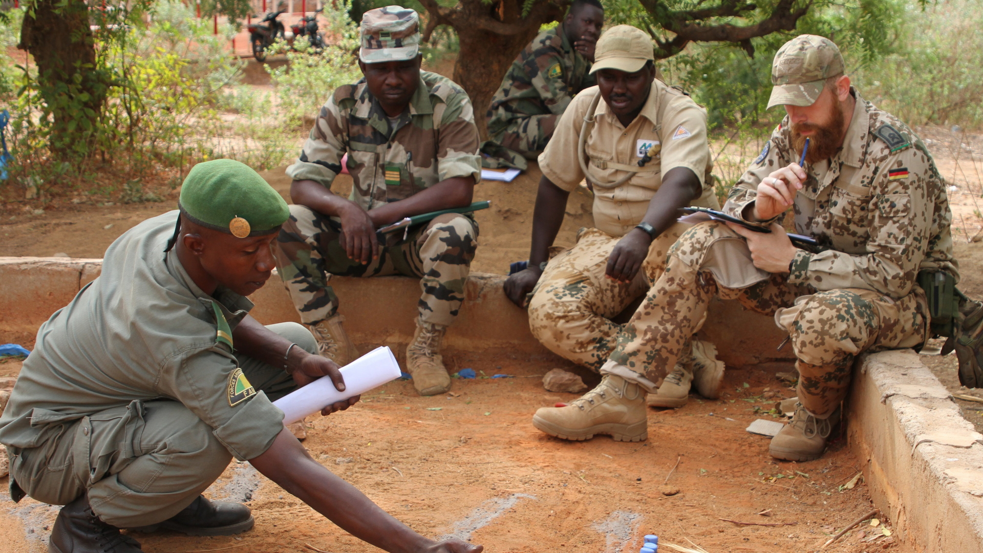 Ein malischer Soldat bespricht während einer EUTM-Übung mit einem deutschen Ausbilder im Geländesandkasten eine Manöverstrategie.