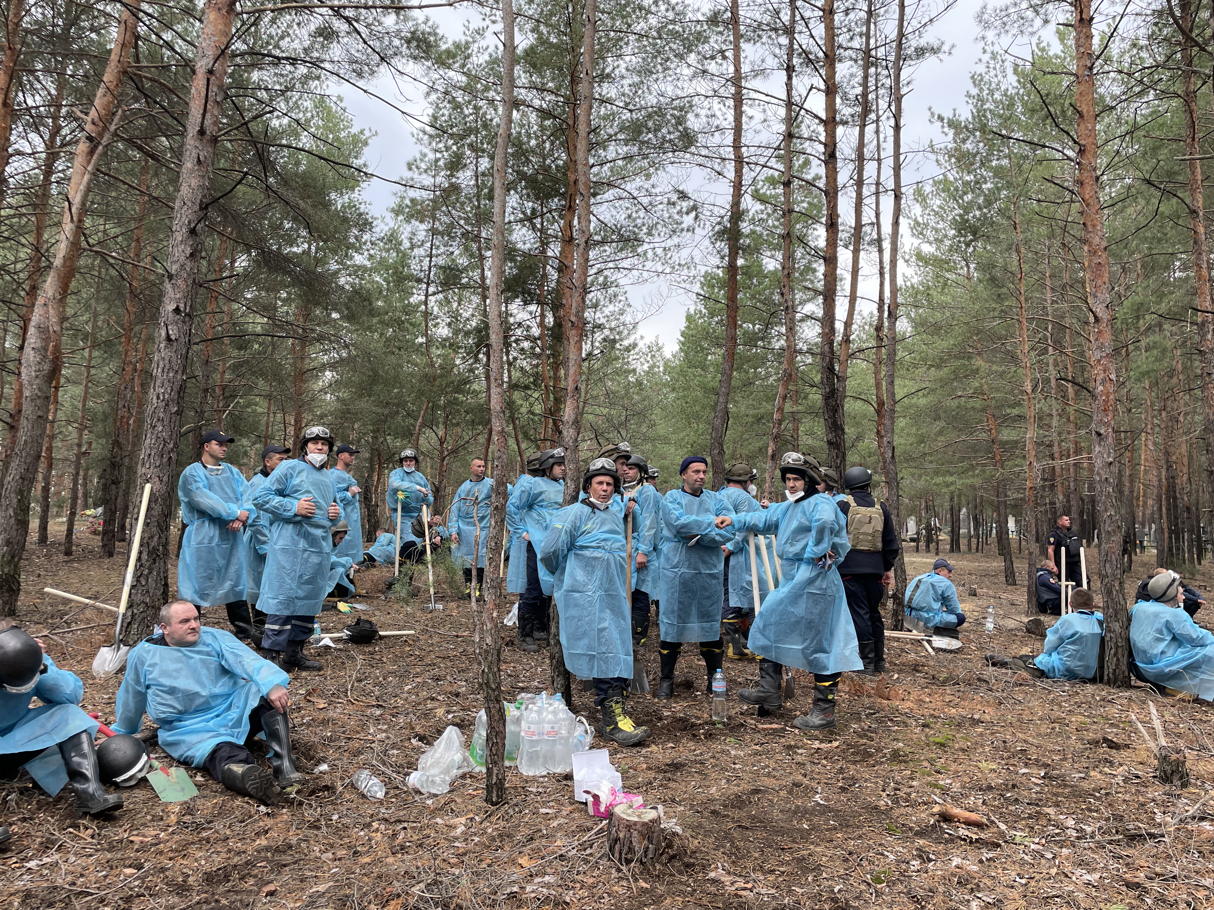 Bei der Exhumierung von Leichen stehen Menschen in Schutzanzügen im Wald nahe der ukrainischen Stadt Isjum. | Andrea Beer, WDR