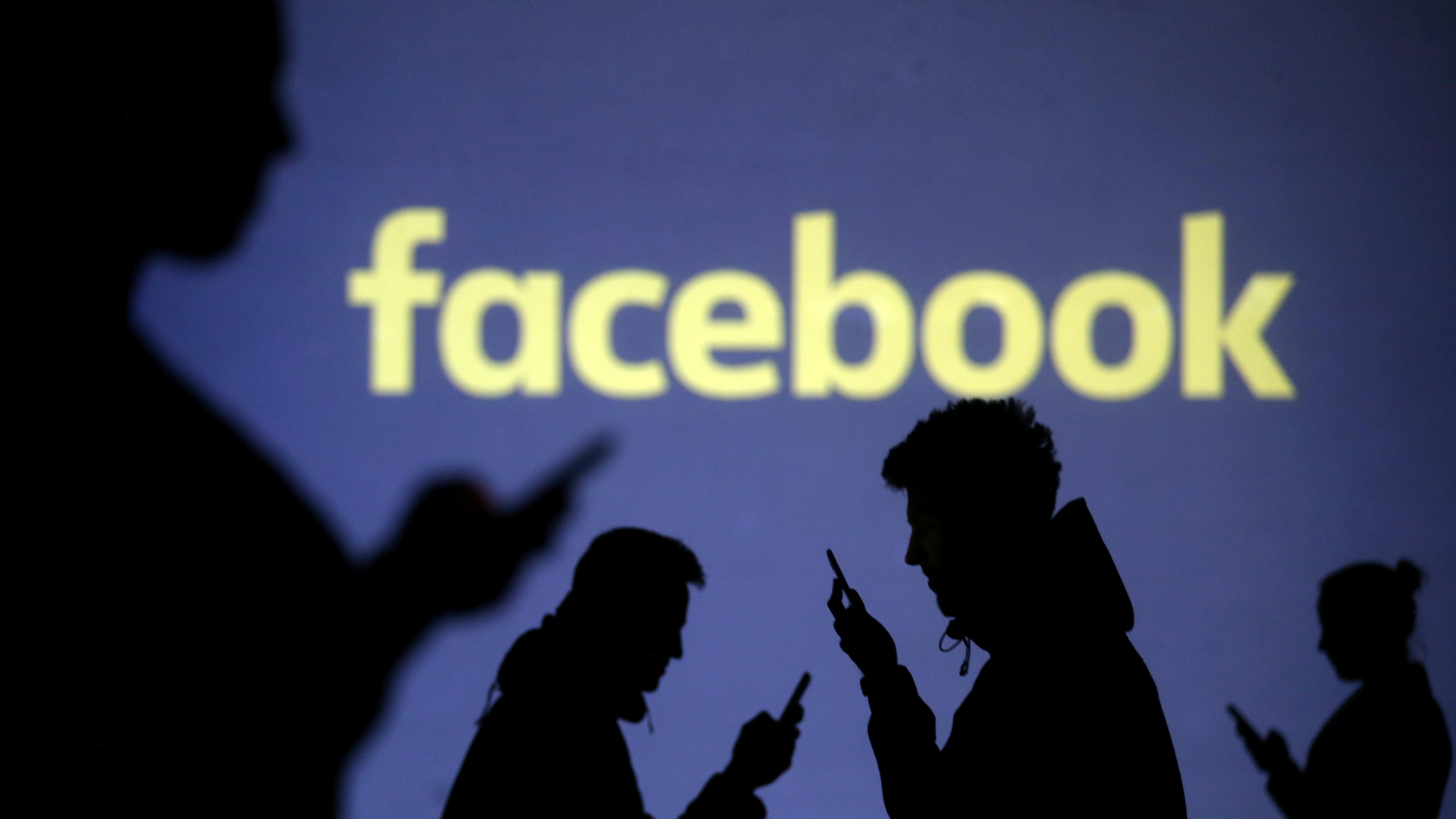 Die Schatten von Menschen, die auf Smartphones schauen, vor dem Facebook-Logo | REUTERS