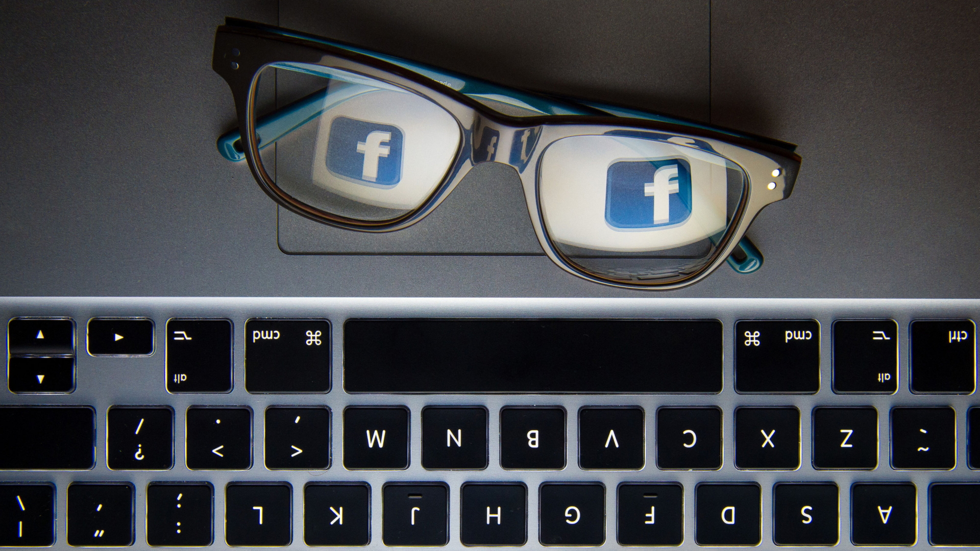 In einer Brille auf einem Laptop spiegelt sich das Logo von Facebook. | dpa