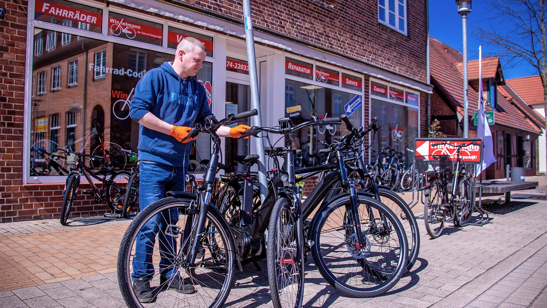 Ein Mitarbeiter stellt Verkaufsräder vor einem  Fahrradladen auf. | picture alliance/dpa/dpa-Zentral