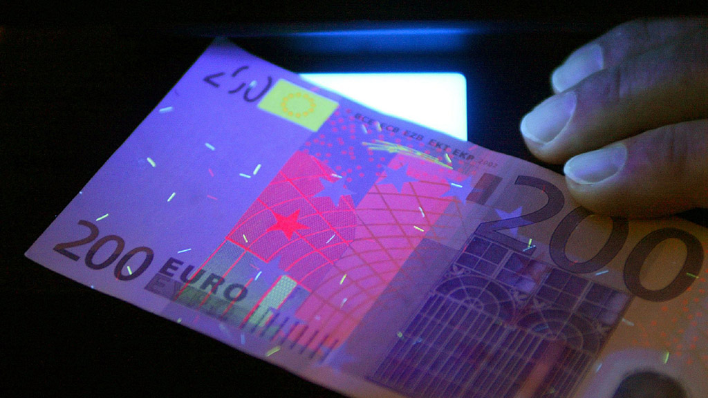 Ein gefälschter 200-Euro-Schein unter einer UV-Lampe. | dpa
