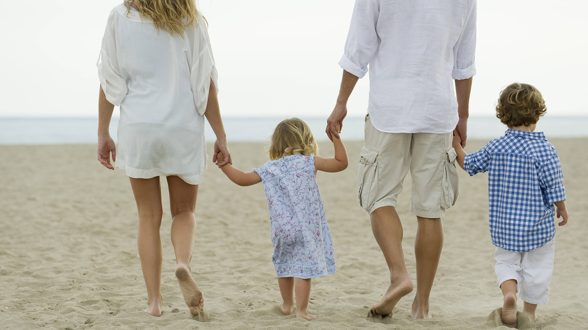 Eine Familie geht am Strand spazieren | imago/PhotoAlto