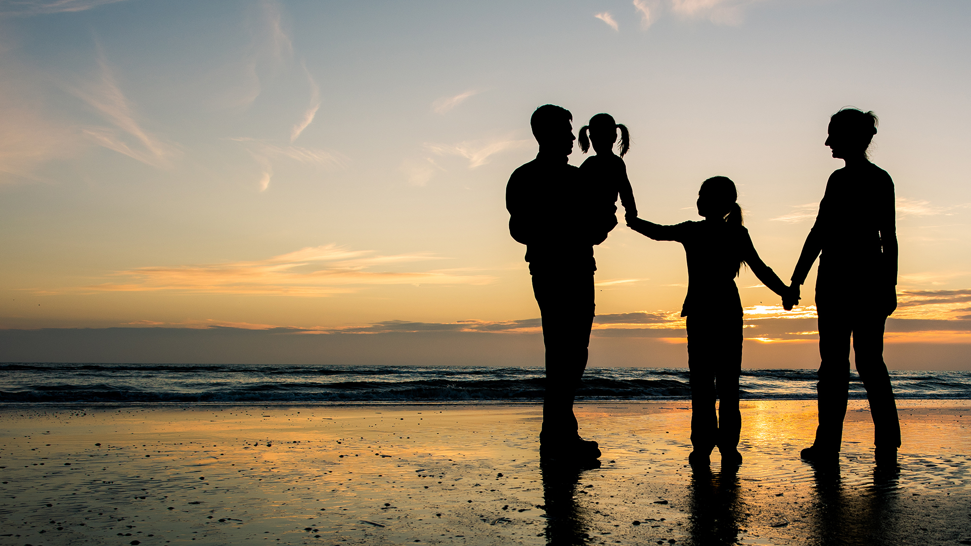 Silhouetten am Strand von Eltern mit zwei Töchtern