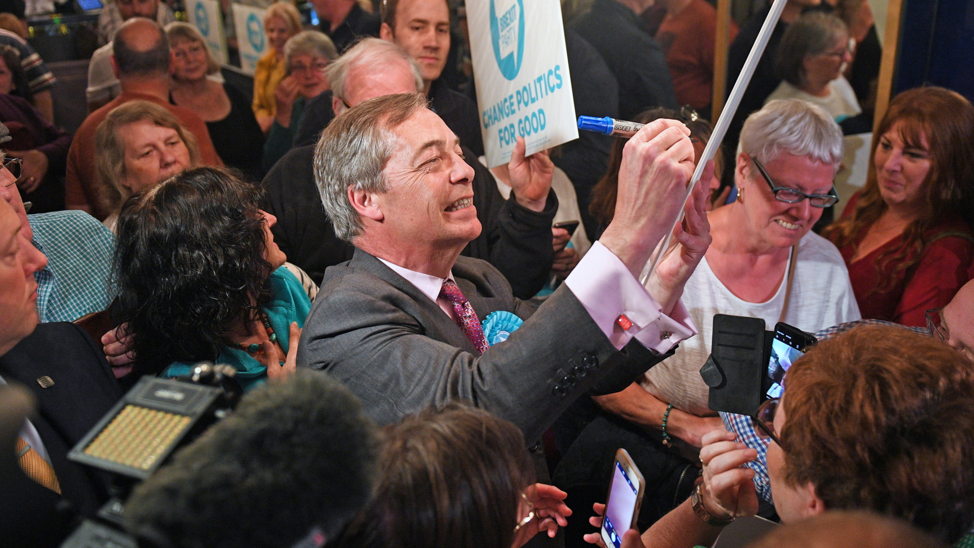 Nigel Farage, EU-Abgeordneter für Großbritannien und Vorsitzender der Brexit-Partei, unterschreibt ein Plakat während einer Wahlkampfveranstaltung. | dpa