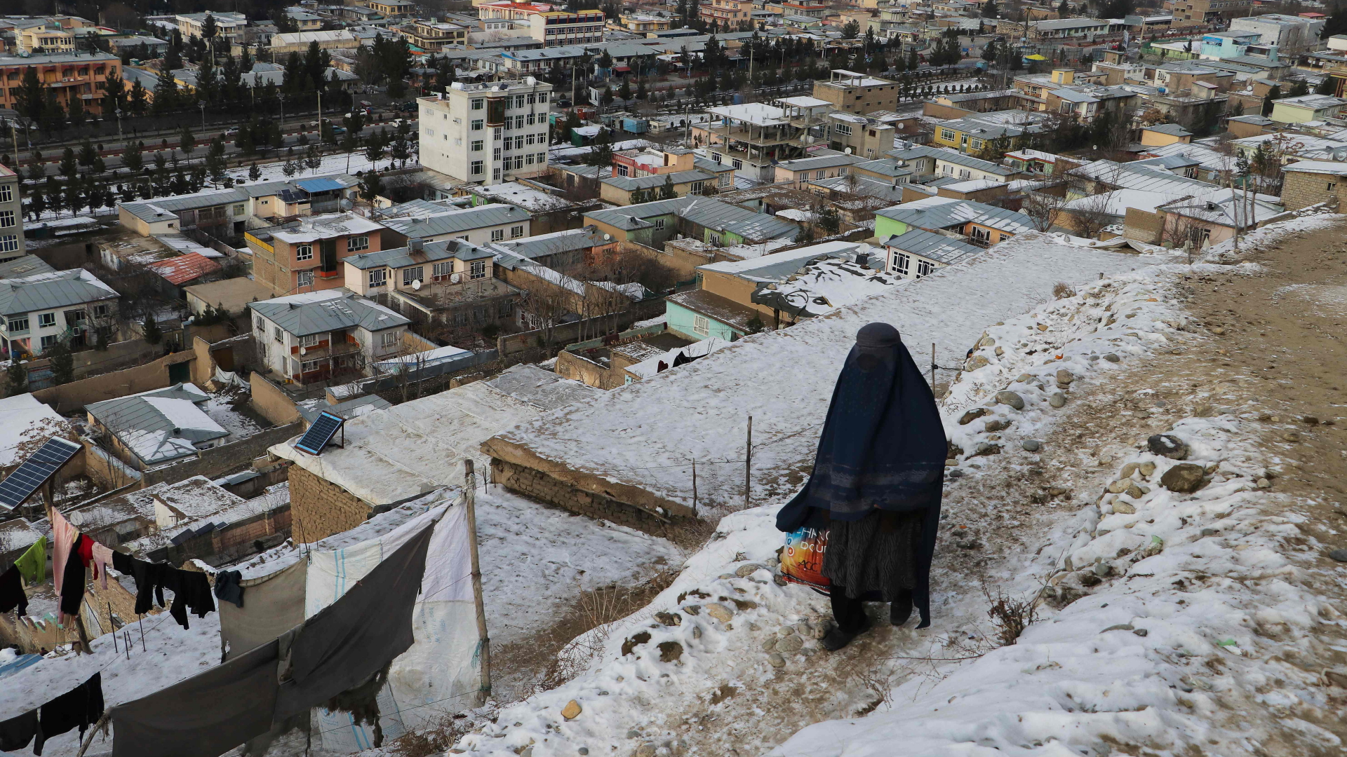 Eine verhüllte Frau blickt an einem kalten Wintertag auf Fayzabad | AFP
