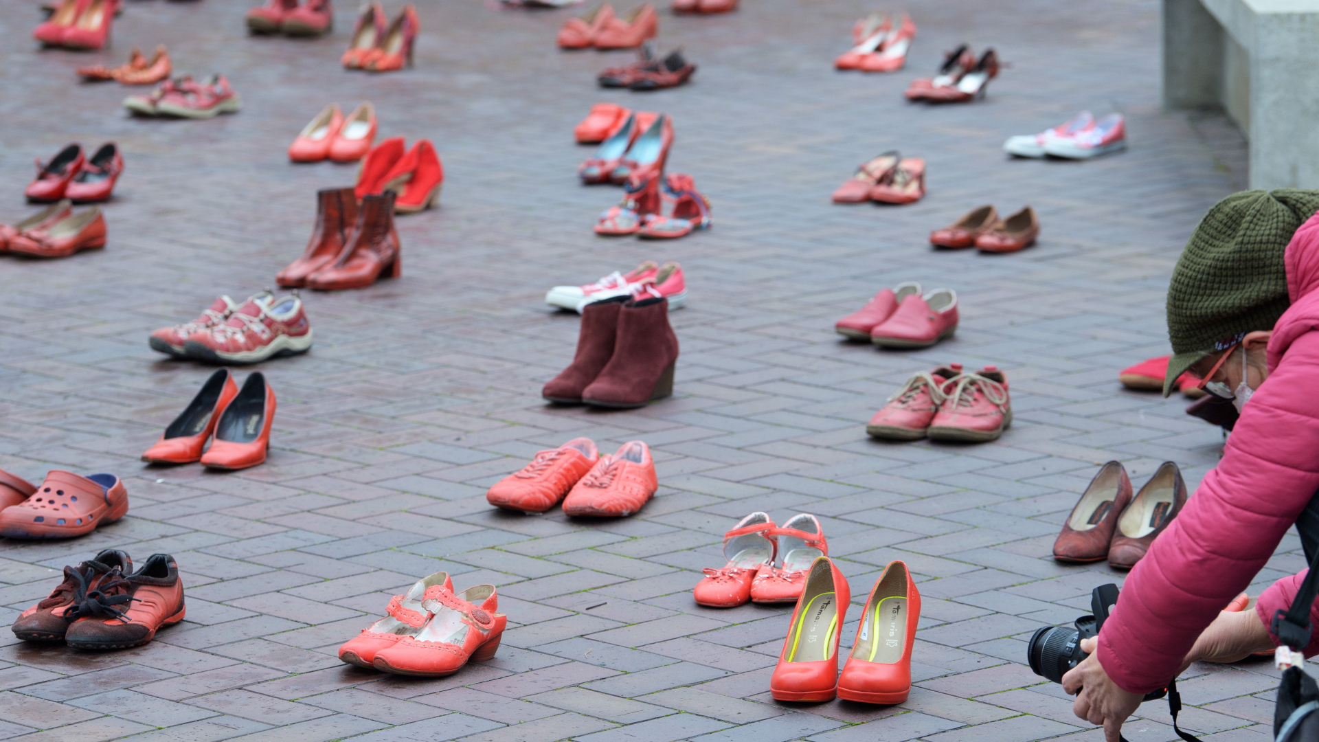 Eine Frau fotografiert rote Schuhe, die in Potsdam vor dem Landtag aufgestellt sind. | dpa