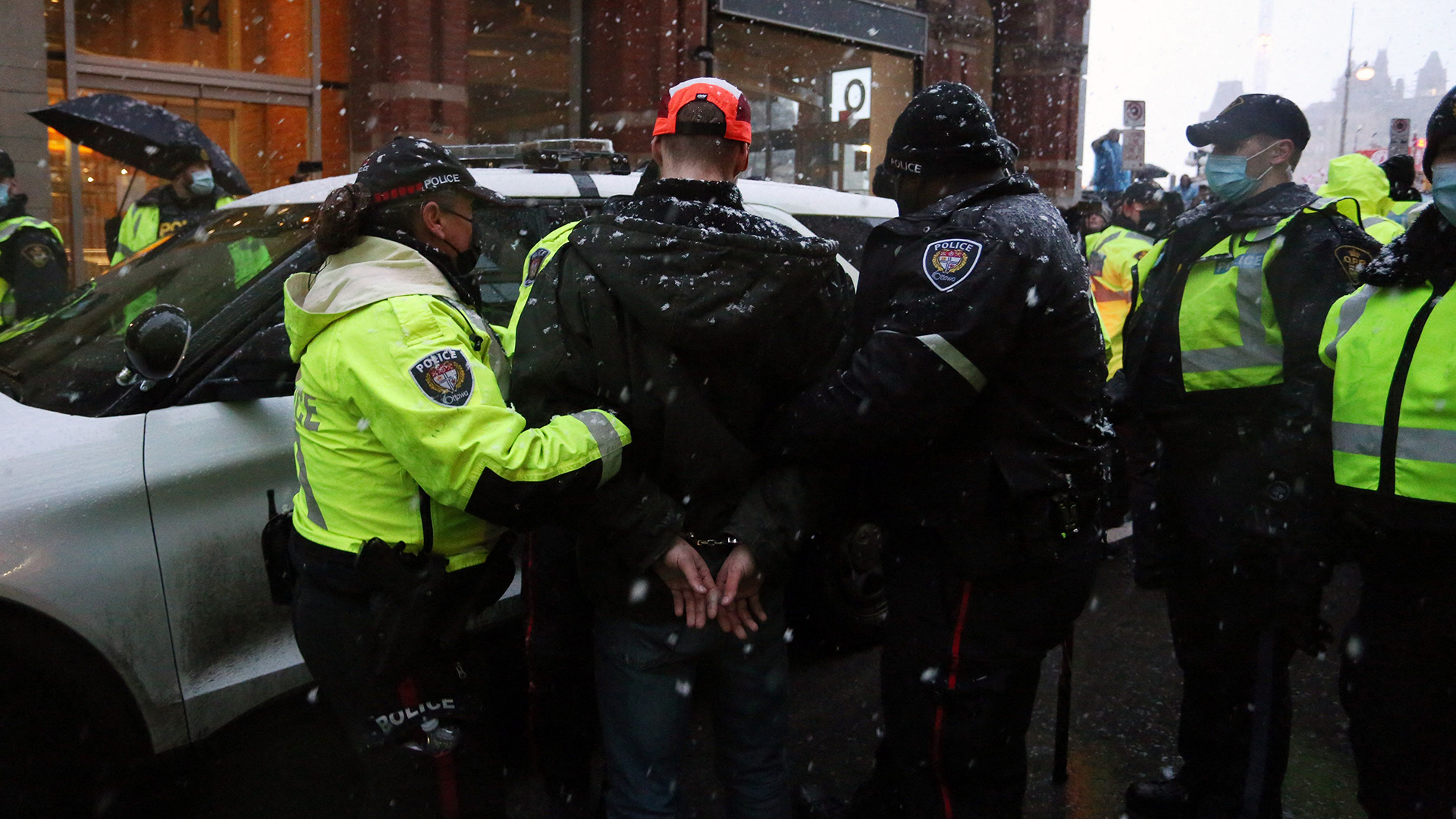 Polizeibeamte eskortieren in Ottawa einen verhafteten Demonstranten zu einem Polizeiauto. | AFP