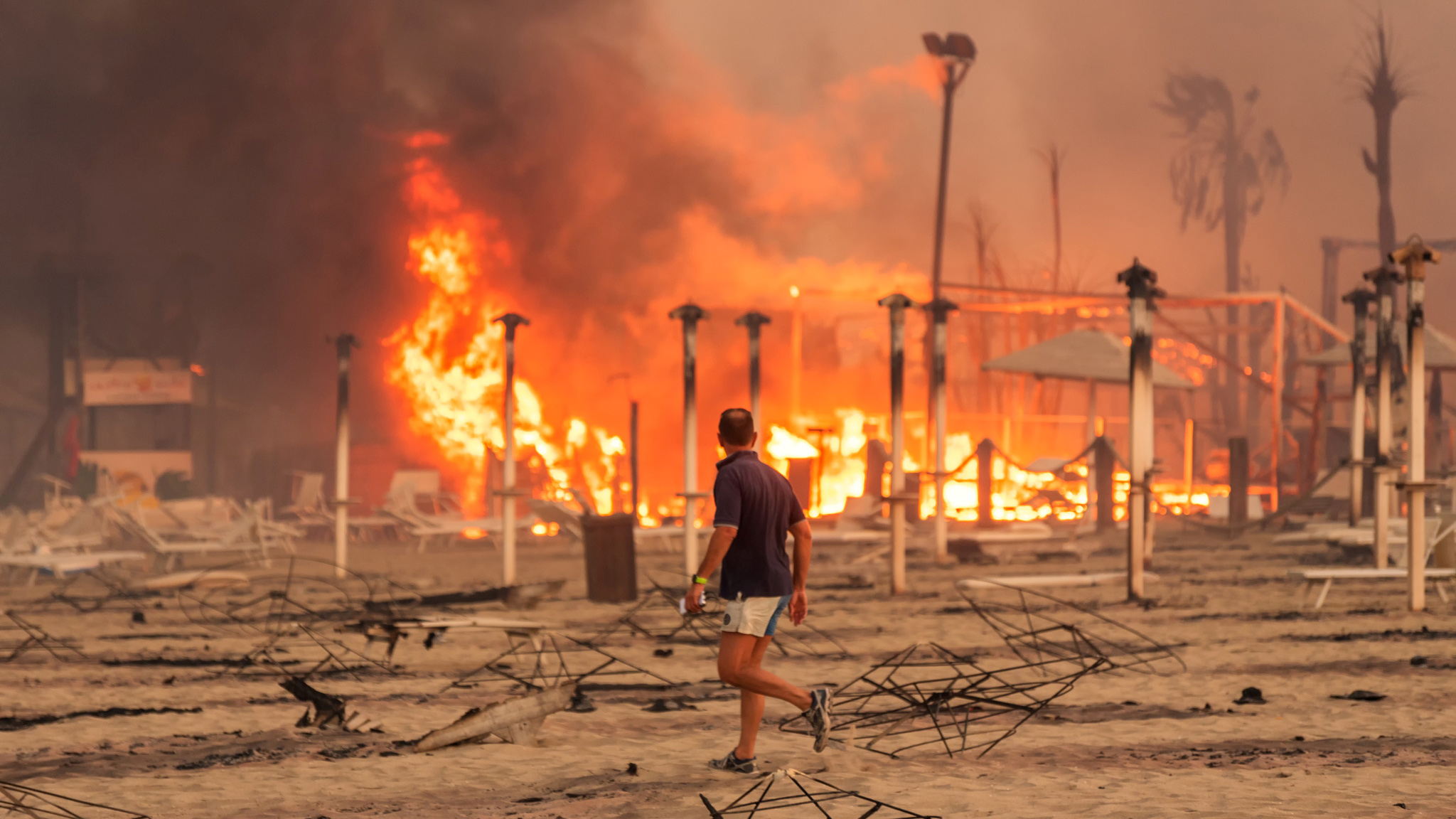 Ein Mann läuft vor einem Feuer in Italien entlang. | ROBERTO VIGLIANISI via REUTERS